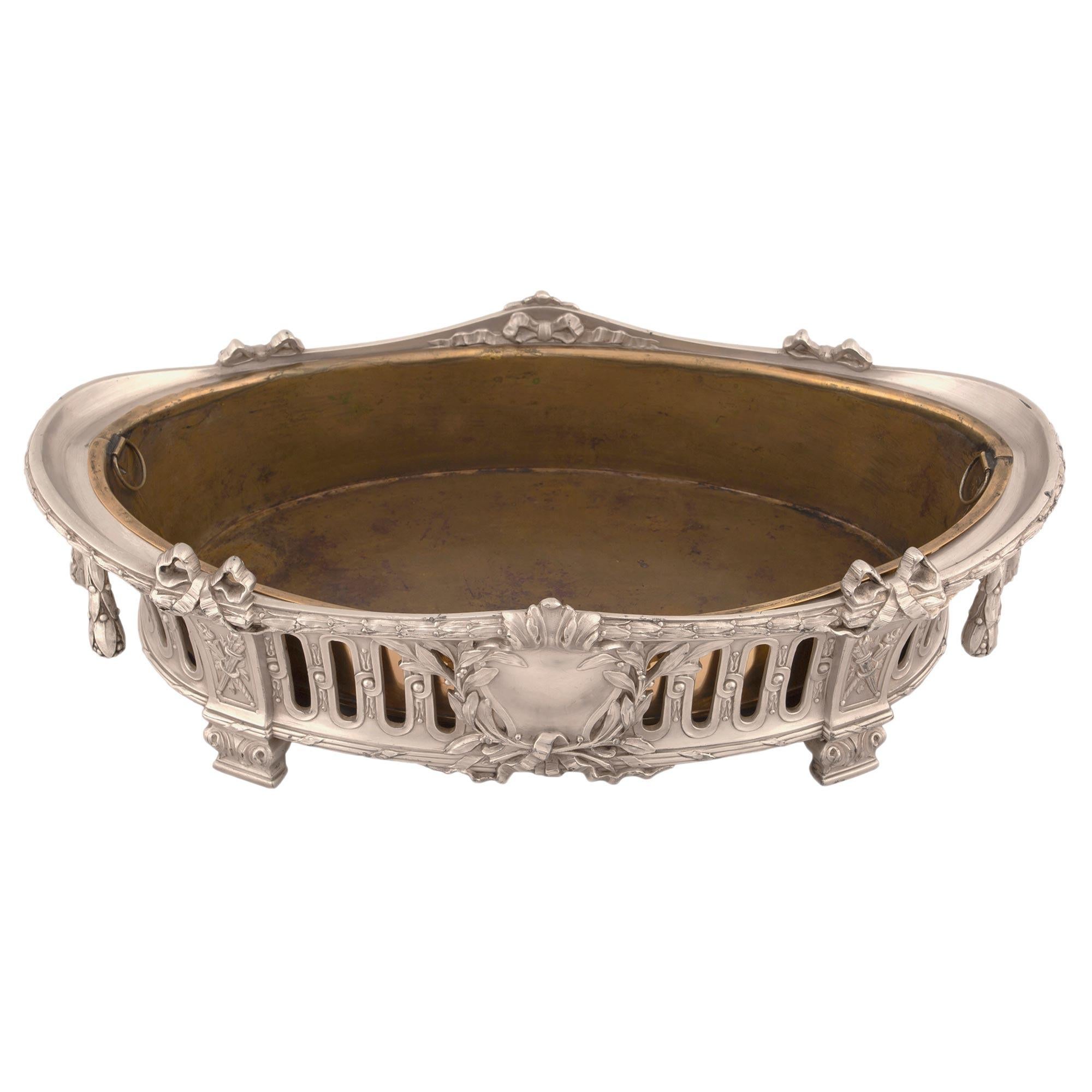 An elegant French 19th century Louis XVI st. silvered bronze centerpiece with its original copper insert. The centerpiece is raised by foliate designed rectangular feet below a detailed quiver and eternal flame with a tied reeded band. At the center