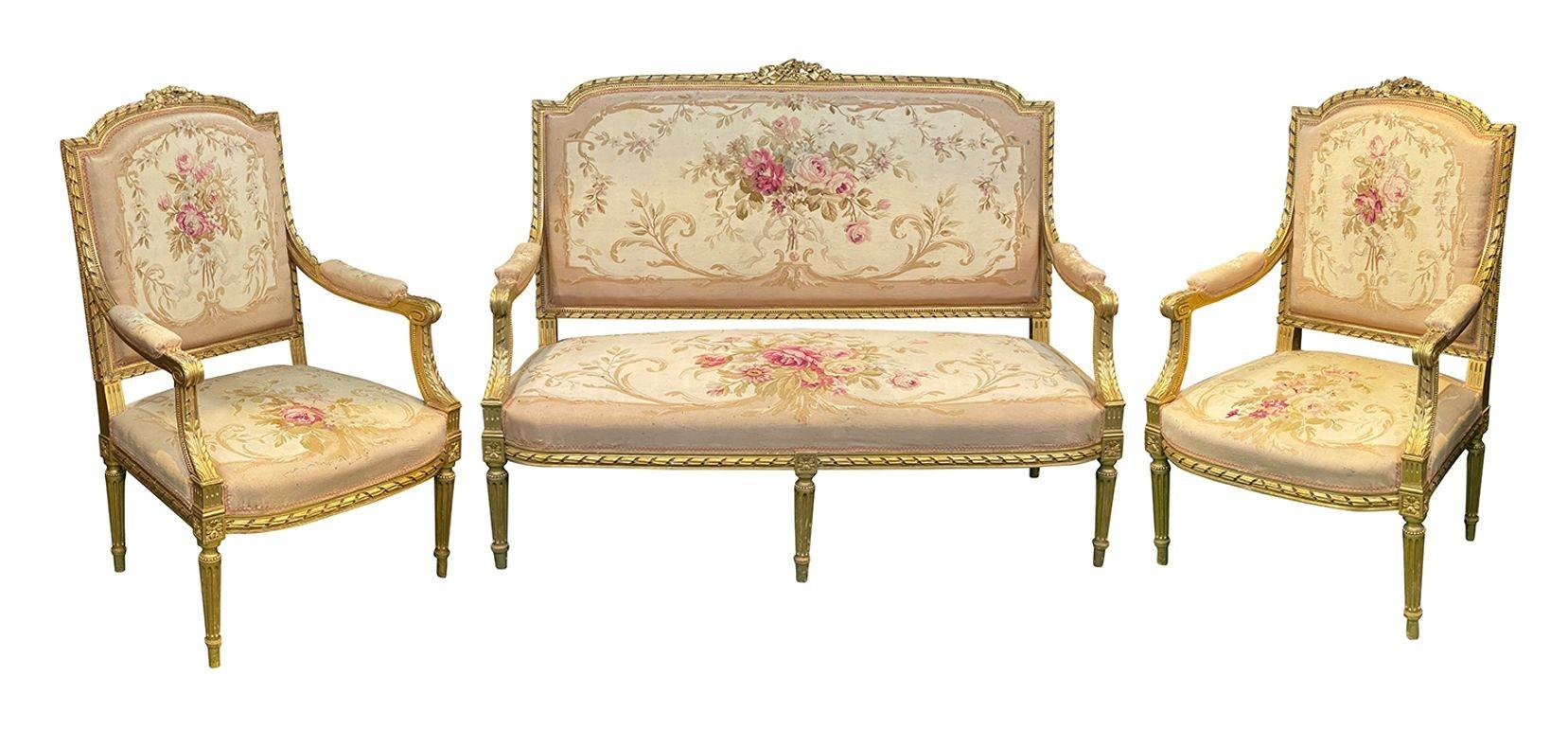 This exquisite French 19th-century Louis XVI style salon suite features five beautifully crafted giltwood pieces, showcasing elegant curves and intricate detailing. The suite includes a settee and four matching chairs, all adorned with luxurious