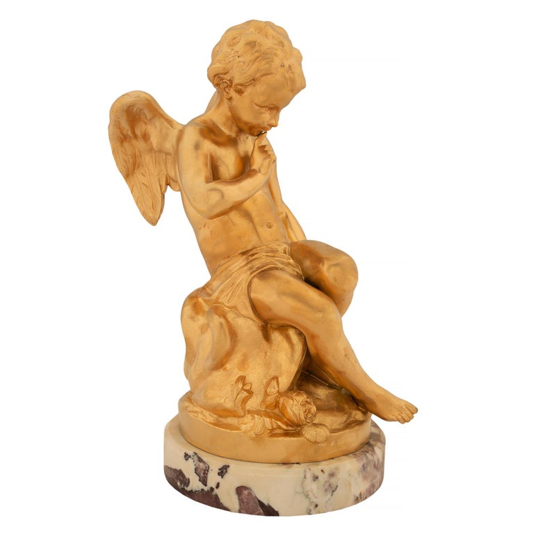A charming and high quality French 19th century Louis XVI st. ormolu and Breche Violette marble statue after Étienne-Maurice Falconet. The statue is raised by a circular marble base with a mottled border. Above, the handsome winged cherub is seated