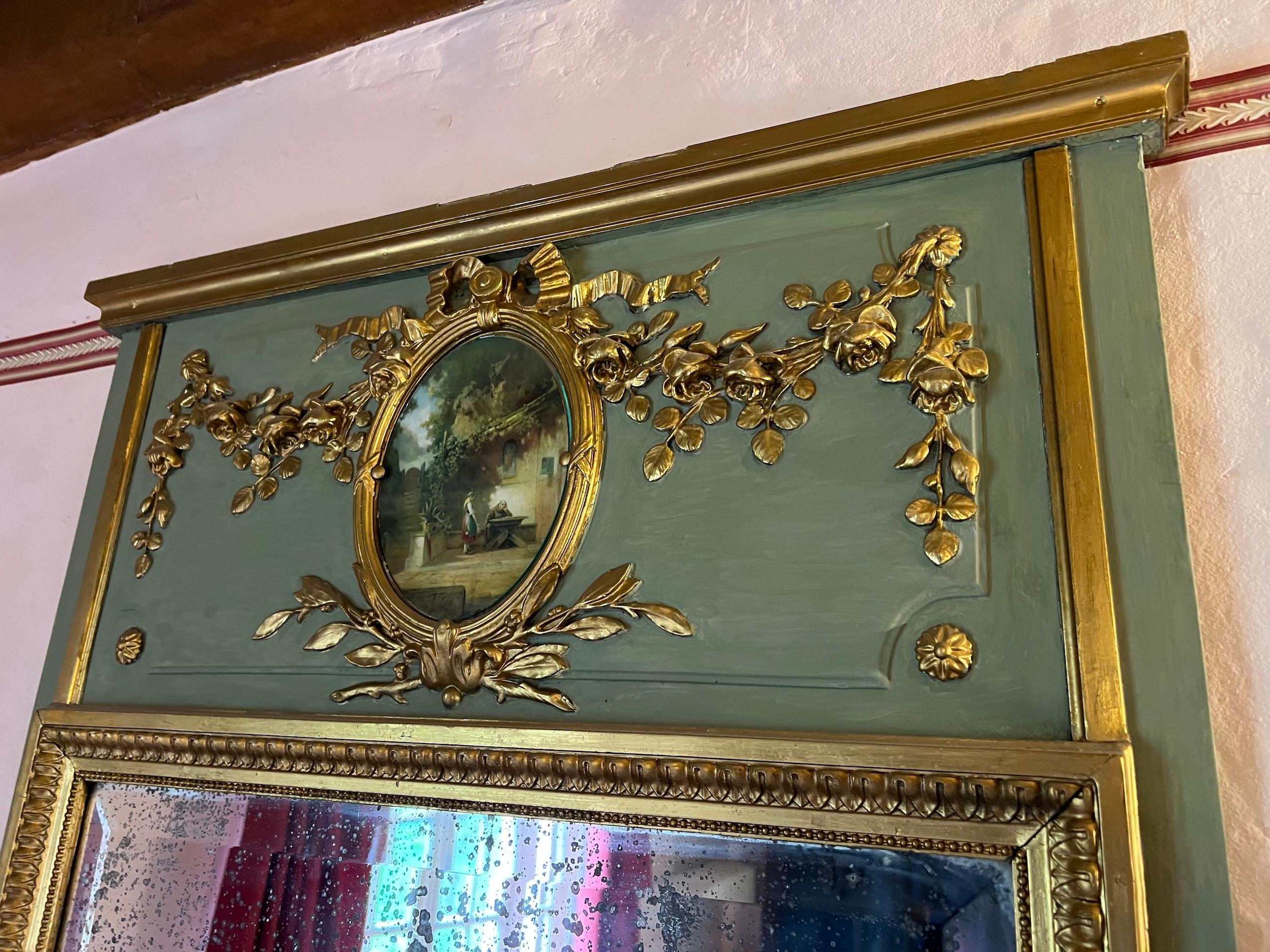 French 19th Century Louis XVI Style Trumeau Mirror
Louis XVI-style trumeau mirror. The painting depicts a countryside scene, enclosed within a medallion crowned by a stucco bow at the top. Adorning the sides are delicate garlands of roses. The