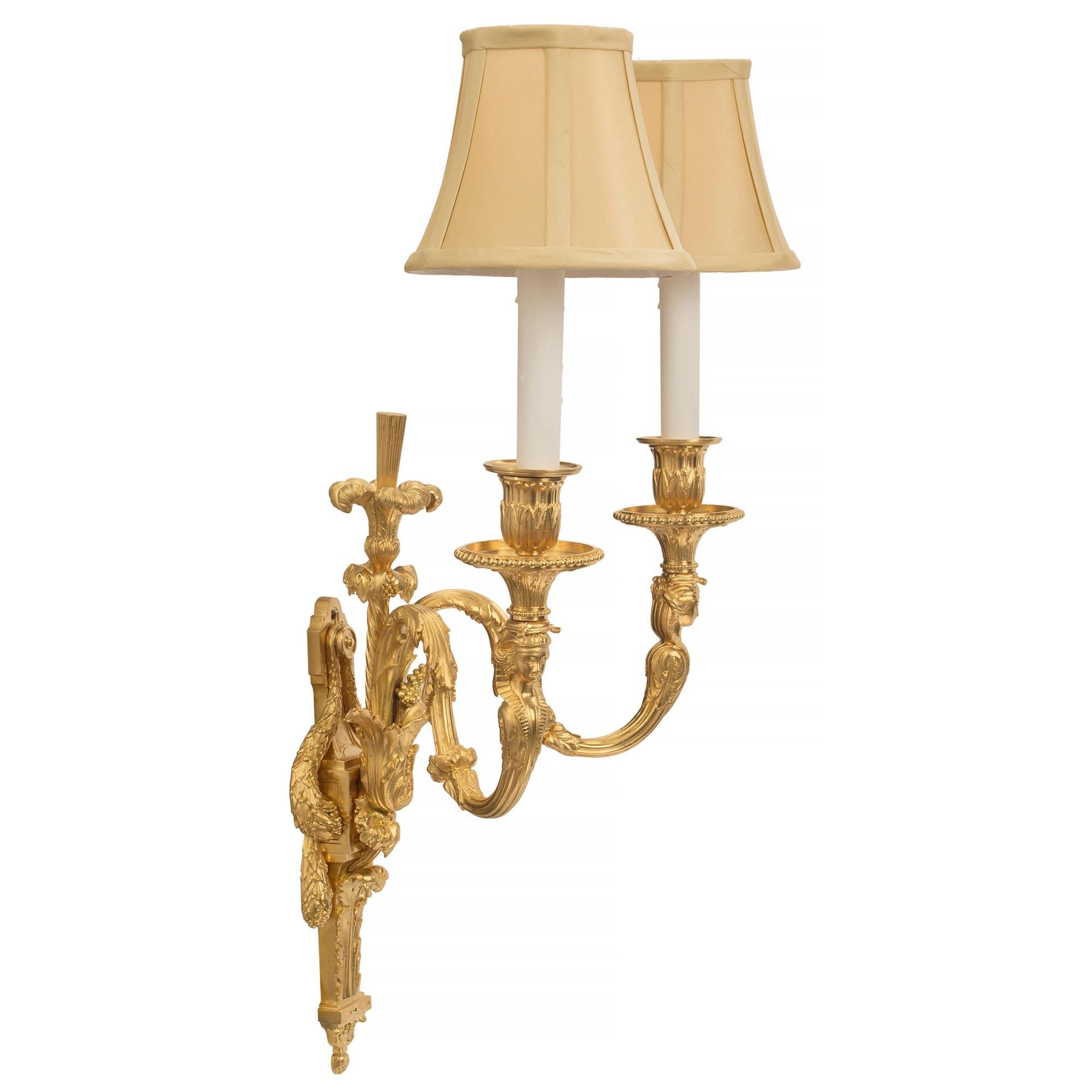 Bellissima coppia di appliques francesi del XIX secolo in stile Luigi XVI a due braccia con ormeggio. Ciascuna applique è centrata da un raffinato terminale inferiore foliato, con foglie d'acanto riccamente arrotolate e una sorprendente riserva