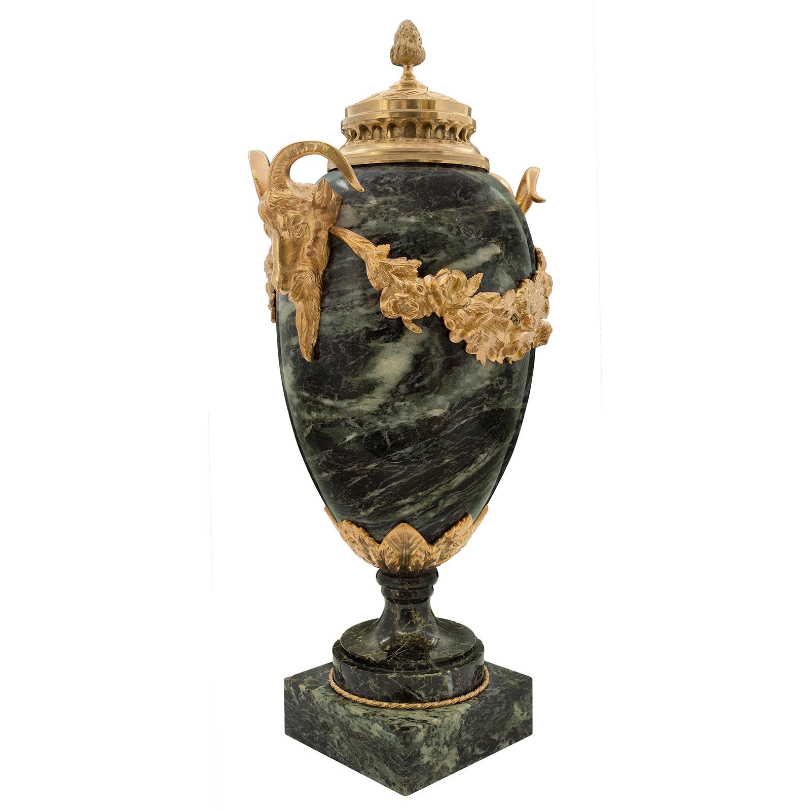 A most elegant pair of French 19th century Louis XVI st. Vert de Patricia marble and ormolu lidded urns. Each urn is raised by a square marble base with a fine circular twisted designed ormolu trim below the socle pedestal with a mottled border.