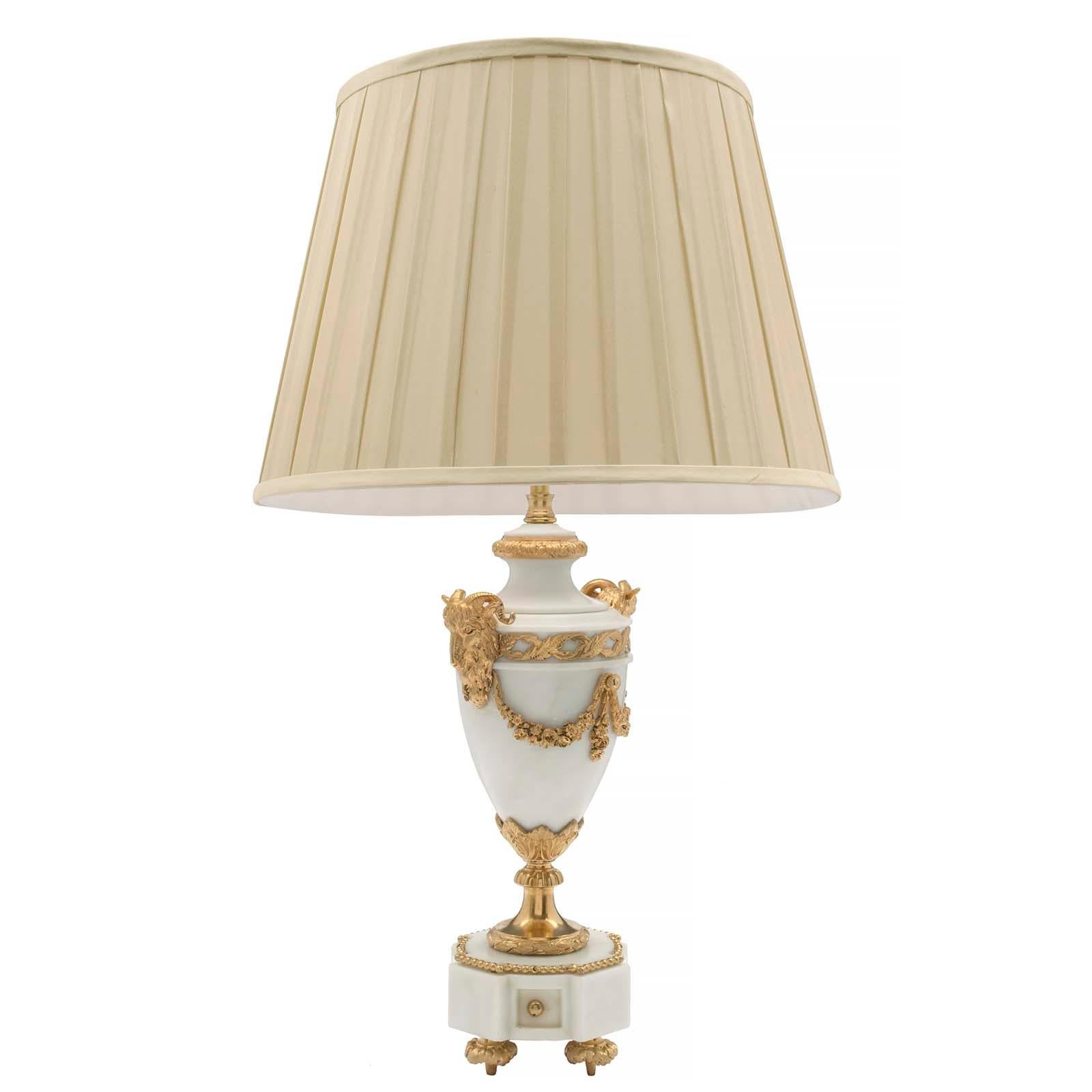 An extremely elegant French 19th century Louis XVI st. white Carrara marble and ormolu lamp. The lamp is raised by ormolu foliate designed topie feet. The octagonal white Carrara marble base has recessed sides accented with ormolu cabochons and a