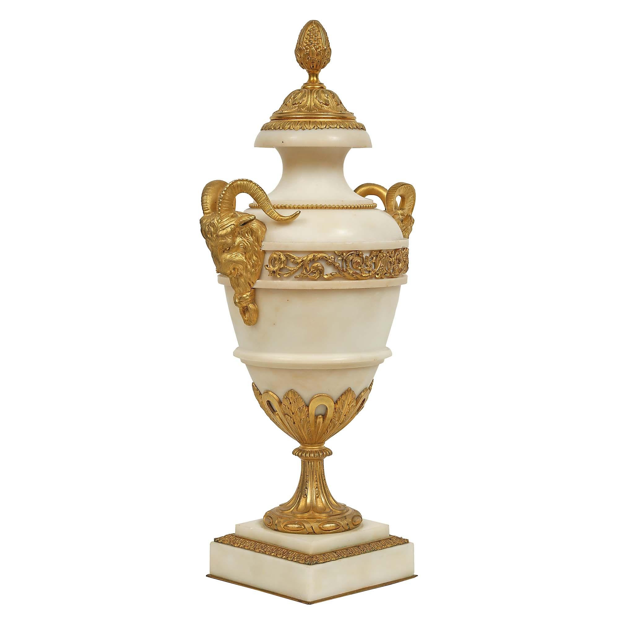 A pair of impressive and large scale, French 19th century Louis XVI st. white Carrara marble and ormolu cassolettes. the urns are raised by a thick stepped marble plinth decorated by an exquisite ormolu acorn leaf designed border. Above is a very