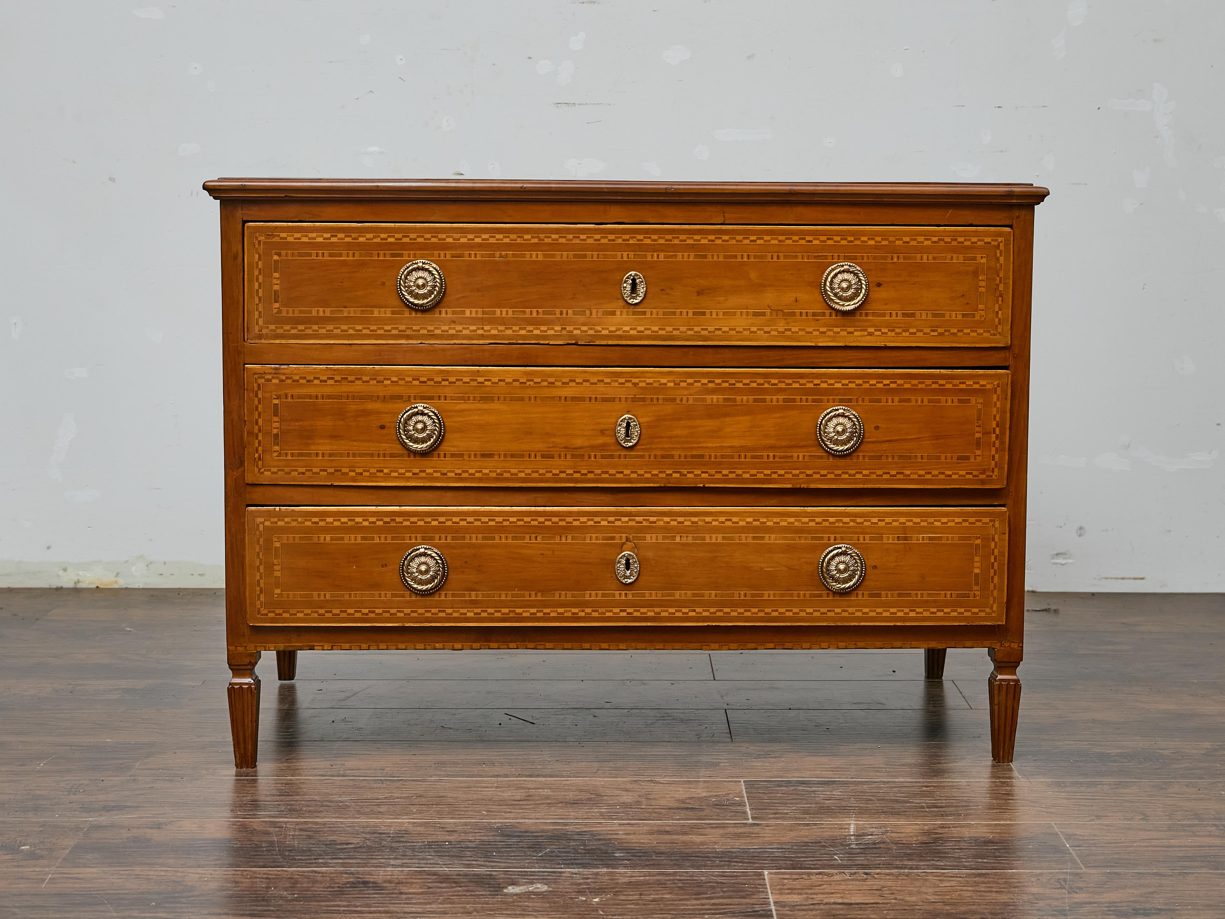 Questo mobile in noce francese del XIX secolo, in stile Luigi XVI, mostra una raffinata maestria artigianale grazie all'intarsio geometrico, alle proporzioni classiche e all'elegante ferramenta in ottone. La silhouette lineare è accentuata da gambe