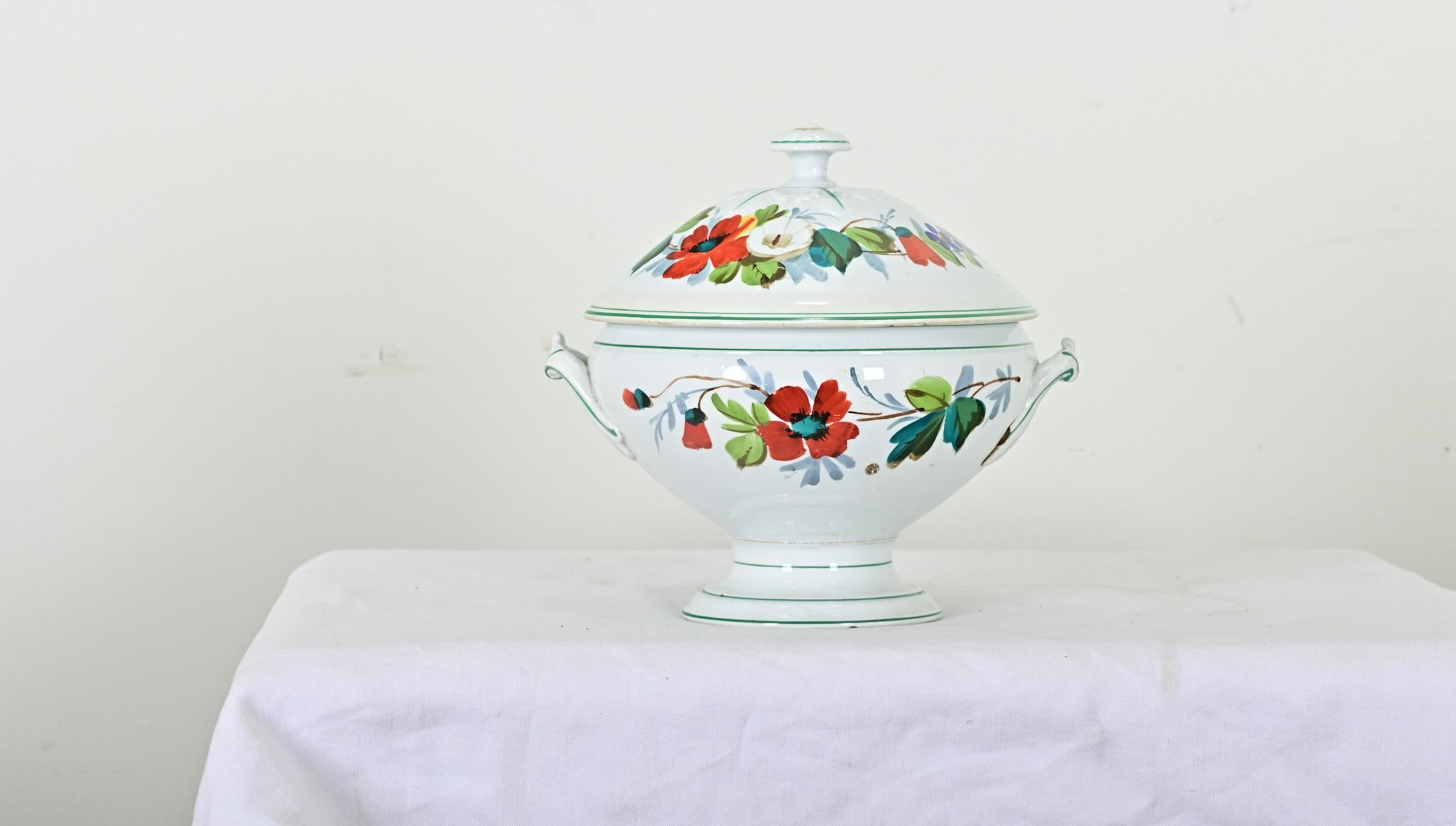 Una deliciosa sopera francesa antigua con base de pedestal, que confiere elegancia a las sopas humildes, los guisos o el gumbo. Esta fina sopera está pintada a mano con delicadas amapolas y otras flores estivales, mientras que un verde ribete