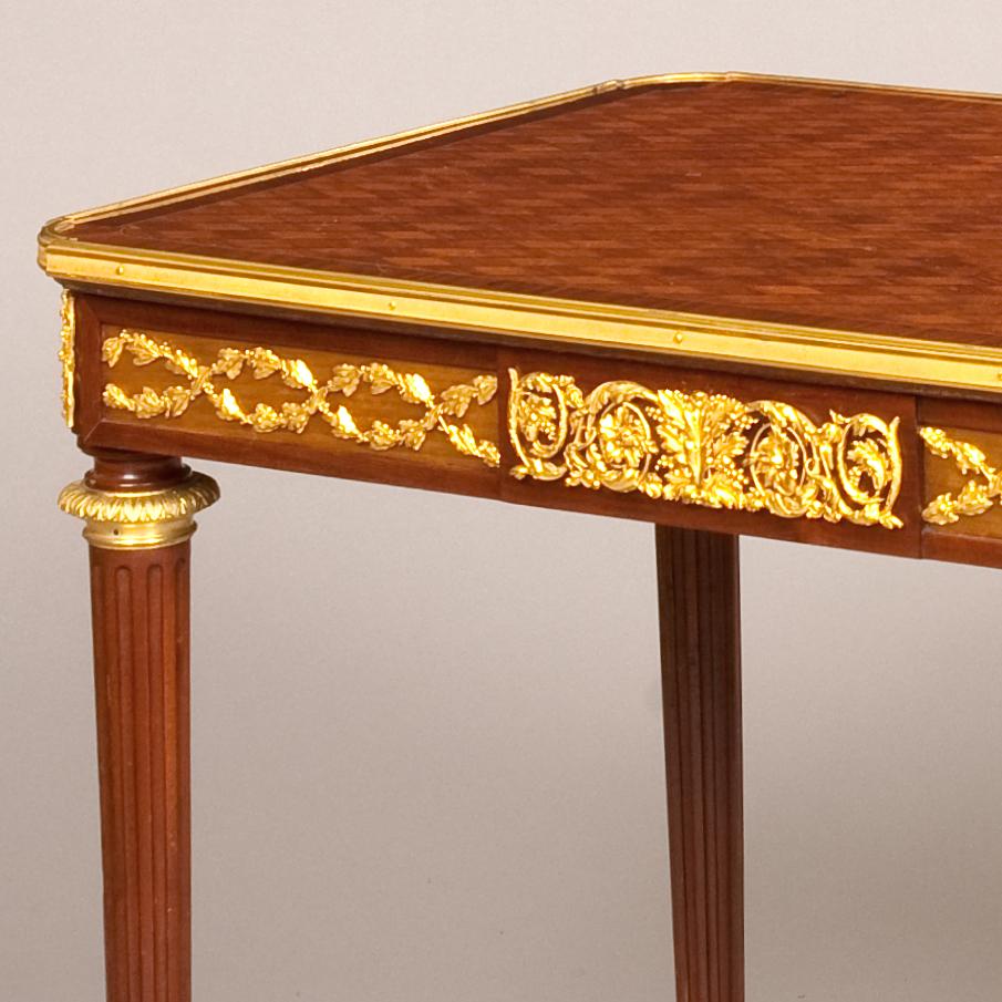 A Fine Side Table signed by Fernand Kohl in the Louis XVI manner

Constructed in mahogany, rising from fluted and tapered cylindrical legs, with acanthus fire gilt bronze sabots, the apron having a centre drawer, with running entre lac foliate