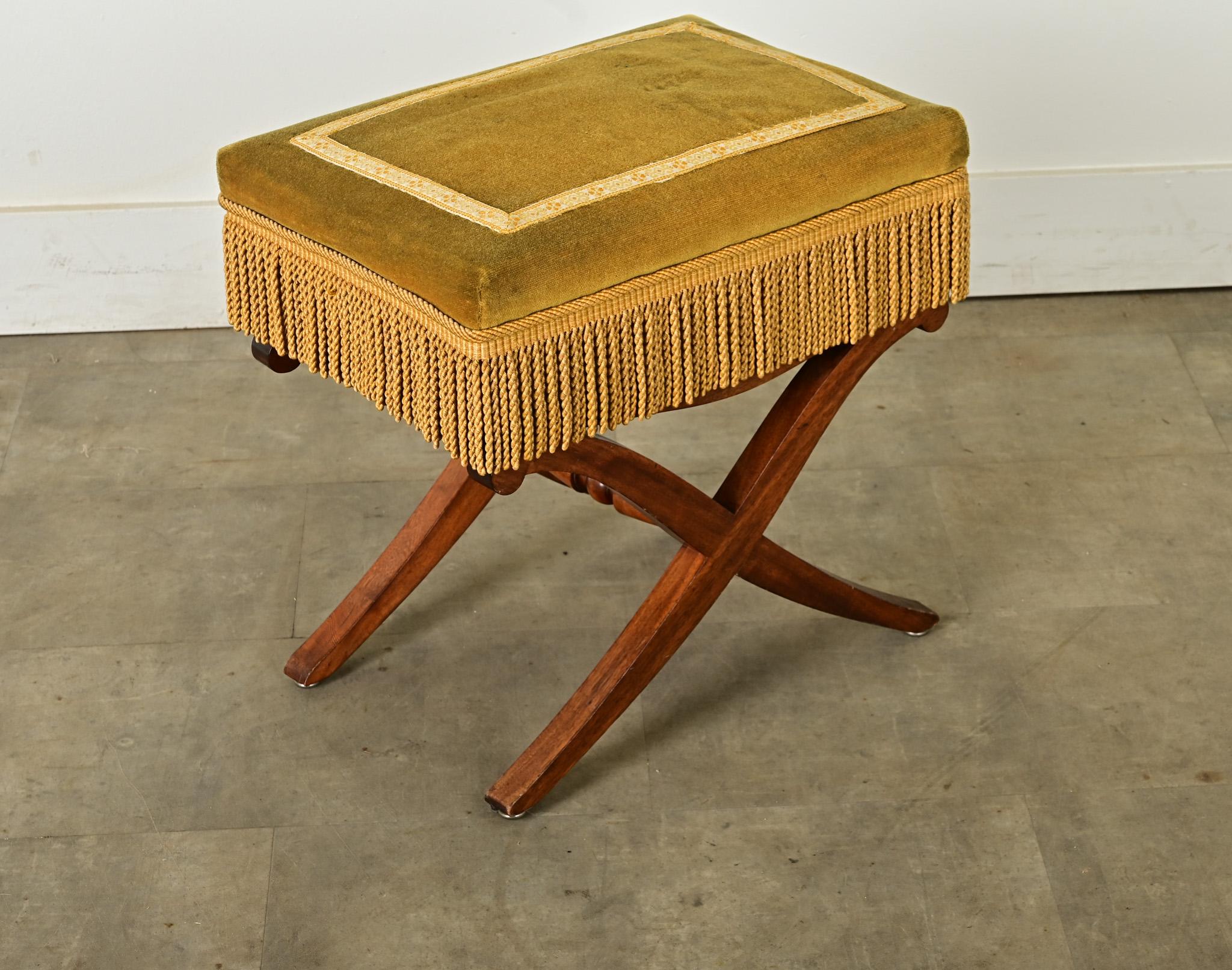 A French mahogany and velvet-upholstered Campaign footstool made in the 1800’s with modern appeal to use anywhere around the home. This comfortable seat is wrapped in a chartreuse velvet, contrasted by a green and orange tape trim framing the