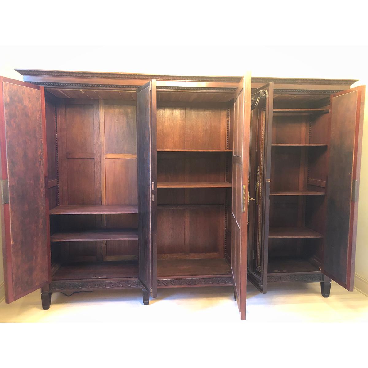 Massive French 19th century mahogany armoire. There are five original plate mirrored doors with some foxing, brass barrel hinges and escutcheons. The two sets of doors on either side are 72-½” H x 18” W and the center door is 72-½” H x 35” W. There