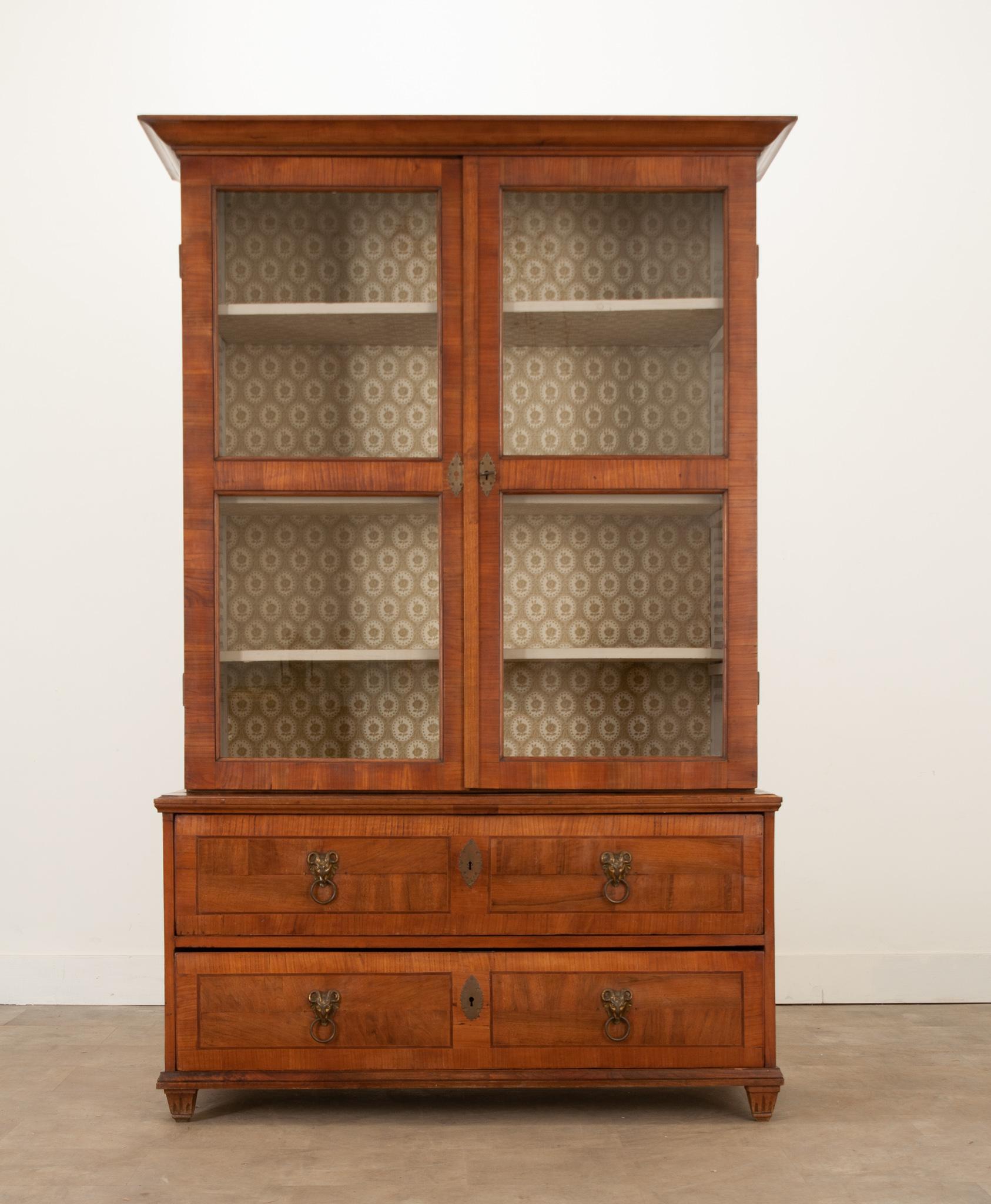 A unique and interesting mahogany bibliotheque from 19th Century France. The bookcase is split into two bodies: a glass-front upper and a lower bank of drawers. The upper body retains its original glass and is accessed using its lock and key. The