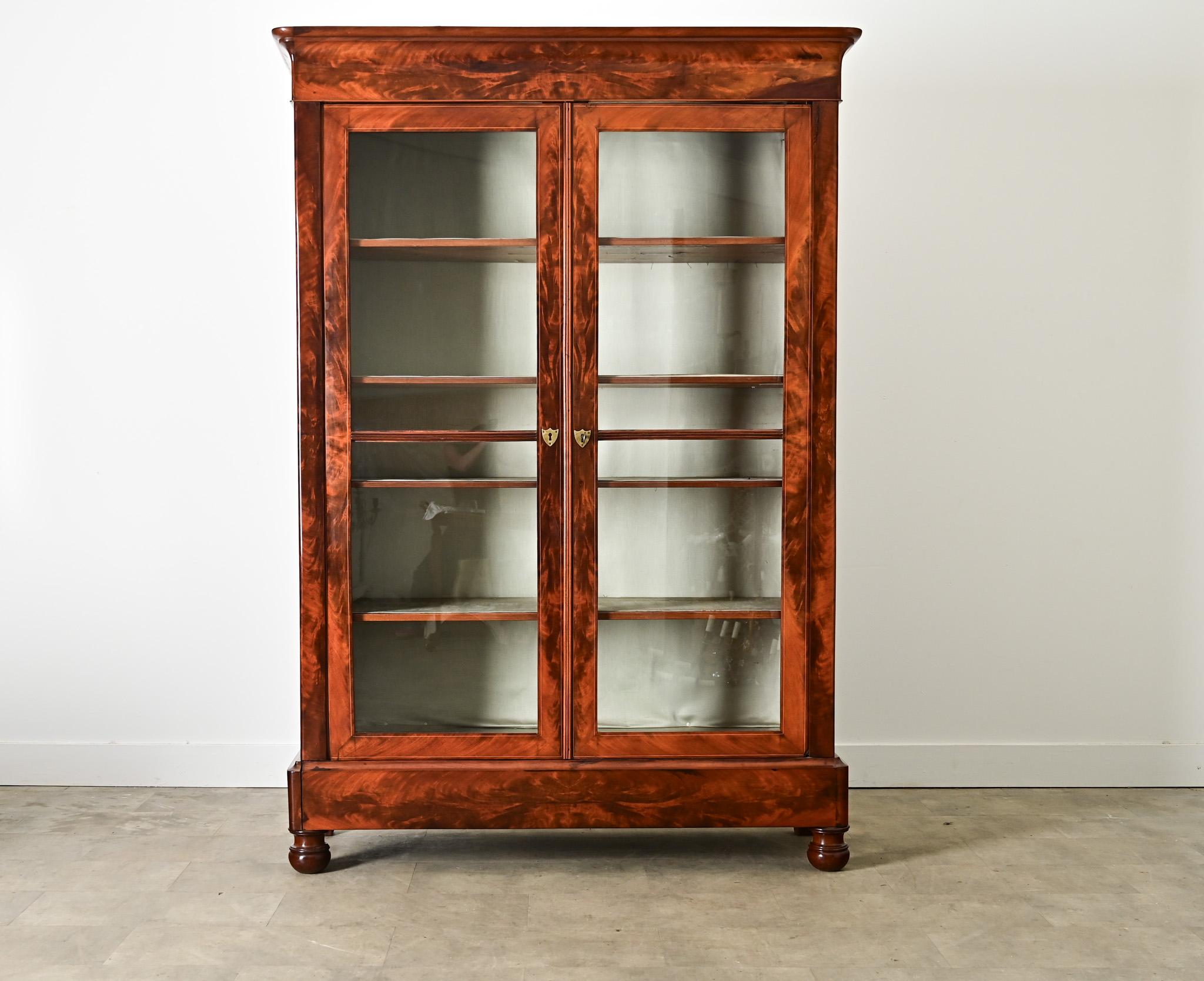 Bibliothèque u otra vitrina francesa del siglo XIX, estilo Louis Philippe, hecha a mano con caoba bellamente labrada y dos puertas de cristal perfiladas con delicadas incrustaciones de tono contrastado. Las líneas limpias y rectas permiten que este