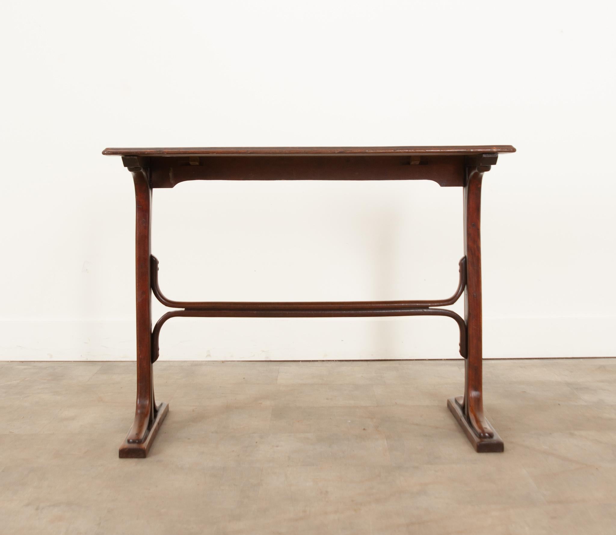 A charming French mahogany bistro table hand-crafted in France during the 19th century. Made entirely of smooth, rich mahogany wood and featuring a molded rectangular top set upon a trestle base with a curved double stretcher for additional support.