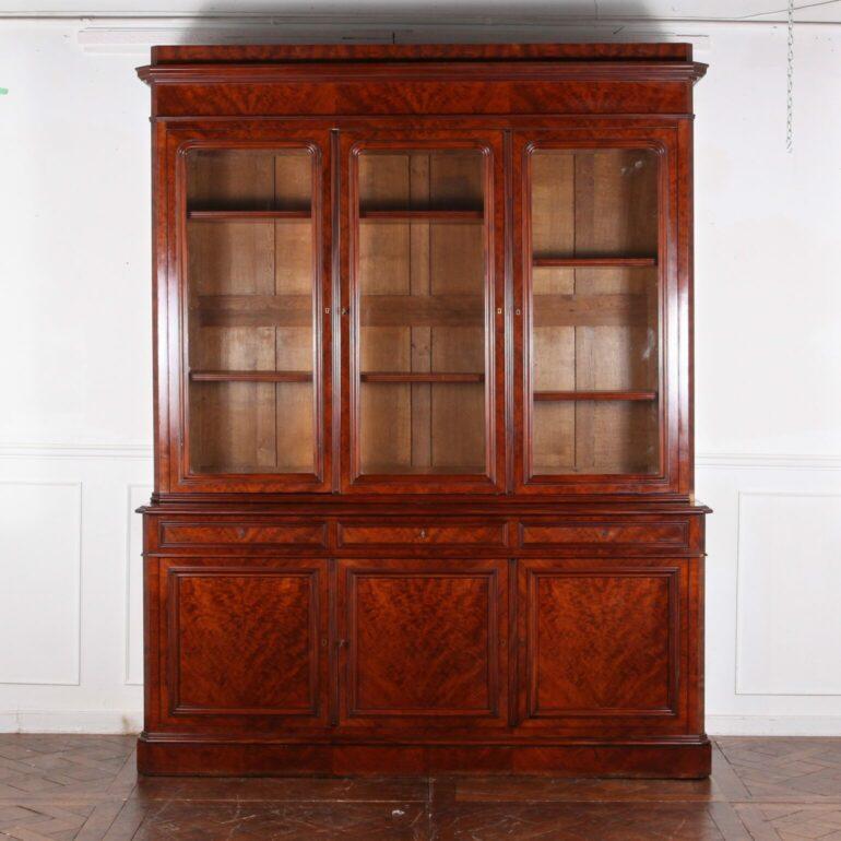 Exceptional, 19th Century French Bookcase in Plum Pudding Mahogany. The tall upper body has 3 glazed doors that showcase a storage cavity that is outfitted with four adjustable shelves. The lower body has 3 panelled doors that close substantial