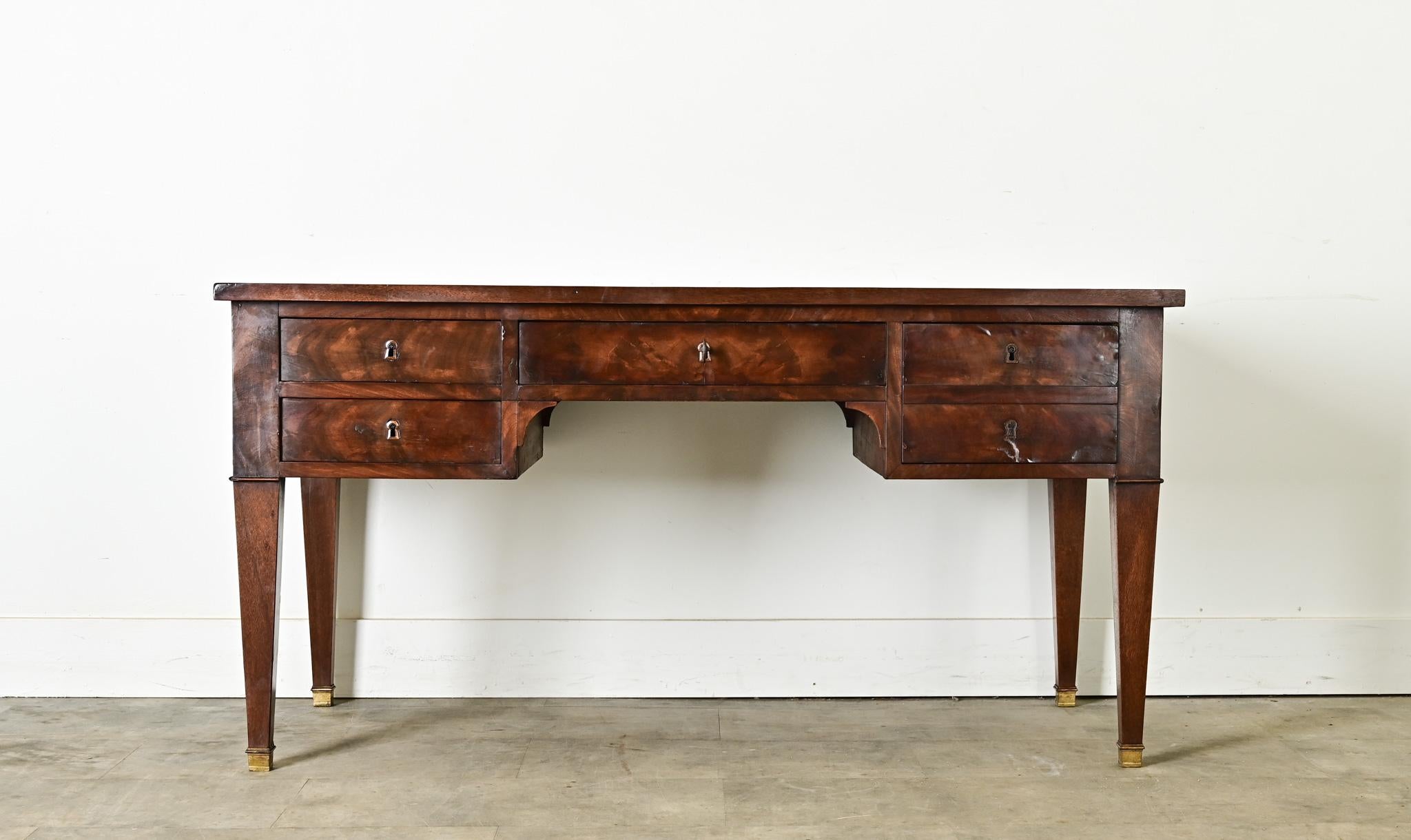 An ingenious leather-topped mahogany desk with hidden extensions on each side to add occasional surface area. The leaves on the sides are still the original emerald green leather framed by gold tooling, whereas the main body has darkened and
