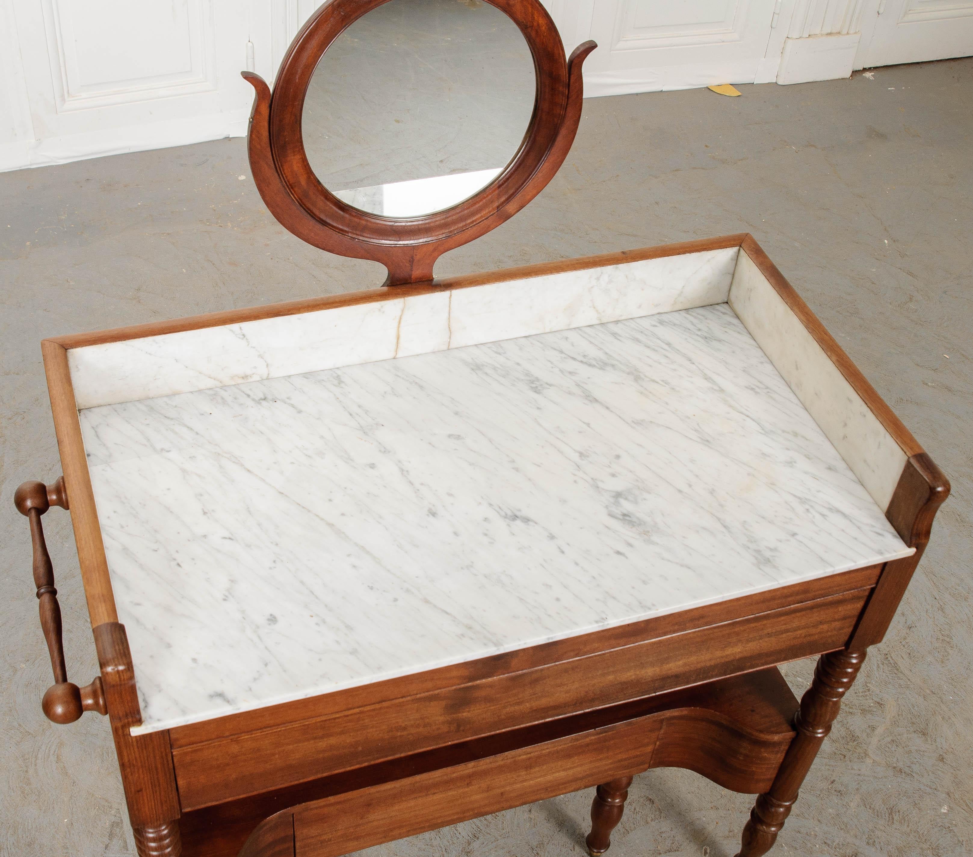 A rewarding beauty regiment begins with vanity. This French 19th century mahogany vanity, in fact! Equipped with a tilting circular mirror, this antique dressing table keeps all things cosmetic in one place. The marble top forgives spilled nail