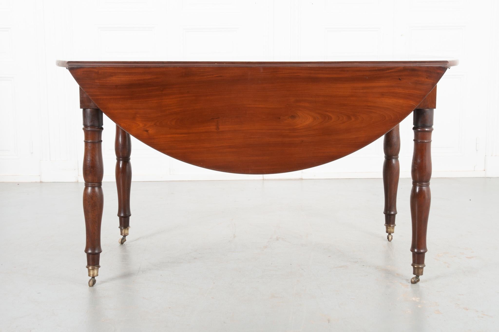 This is an elegant drop leaf table from 19th century France, made from a rich mahogany that's been polished for an exceptional shine. In the past this table also extended from the center, however it is now stationary. The beautiful turned legs