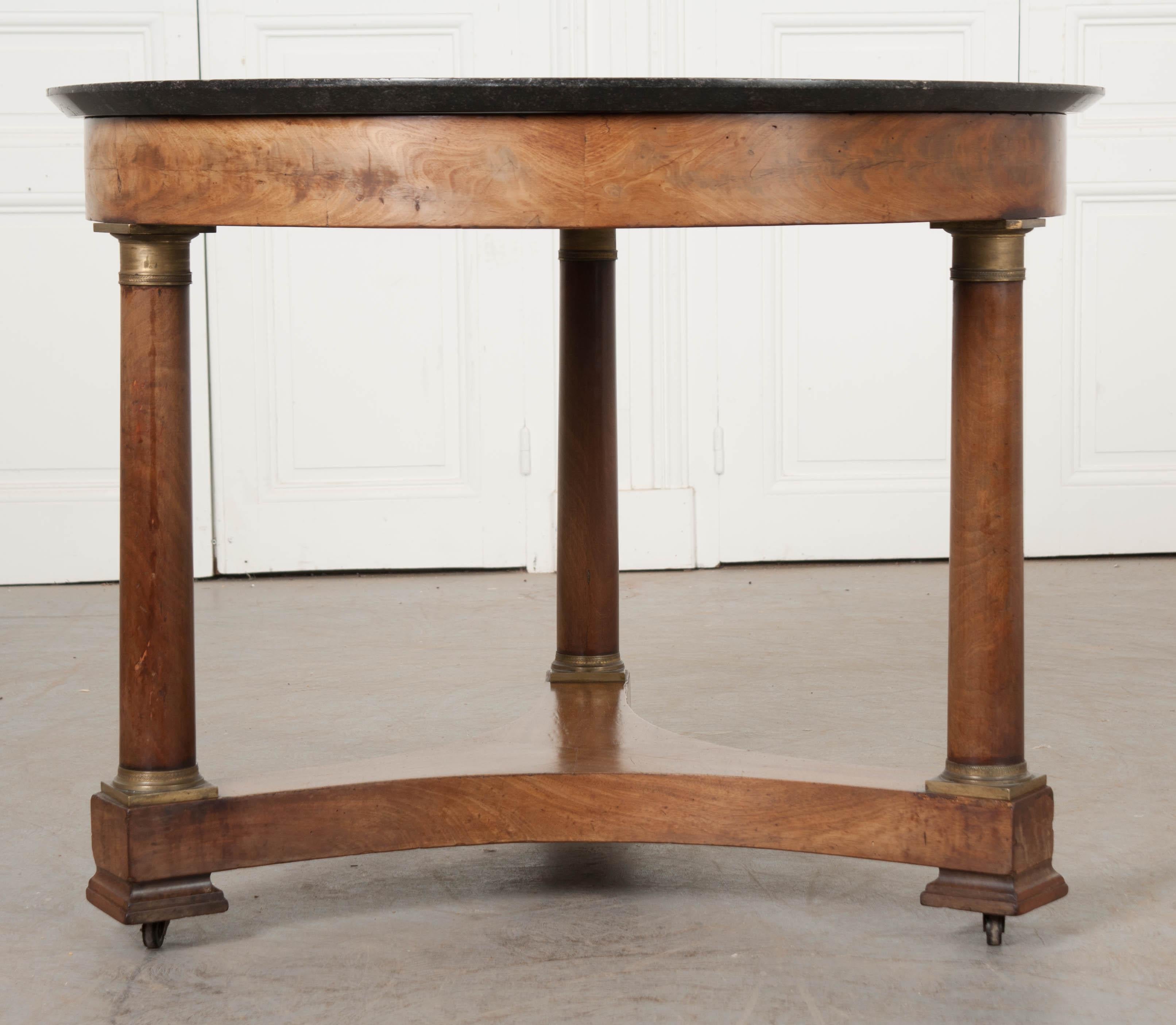 A beautiful, large French Empire round center table with marble top. The black fossil marble top is in wonderful condition and rests atop the circular mahogany veneered apron. The beautifully patinated marble is slightly welled and has an amazing