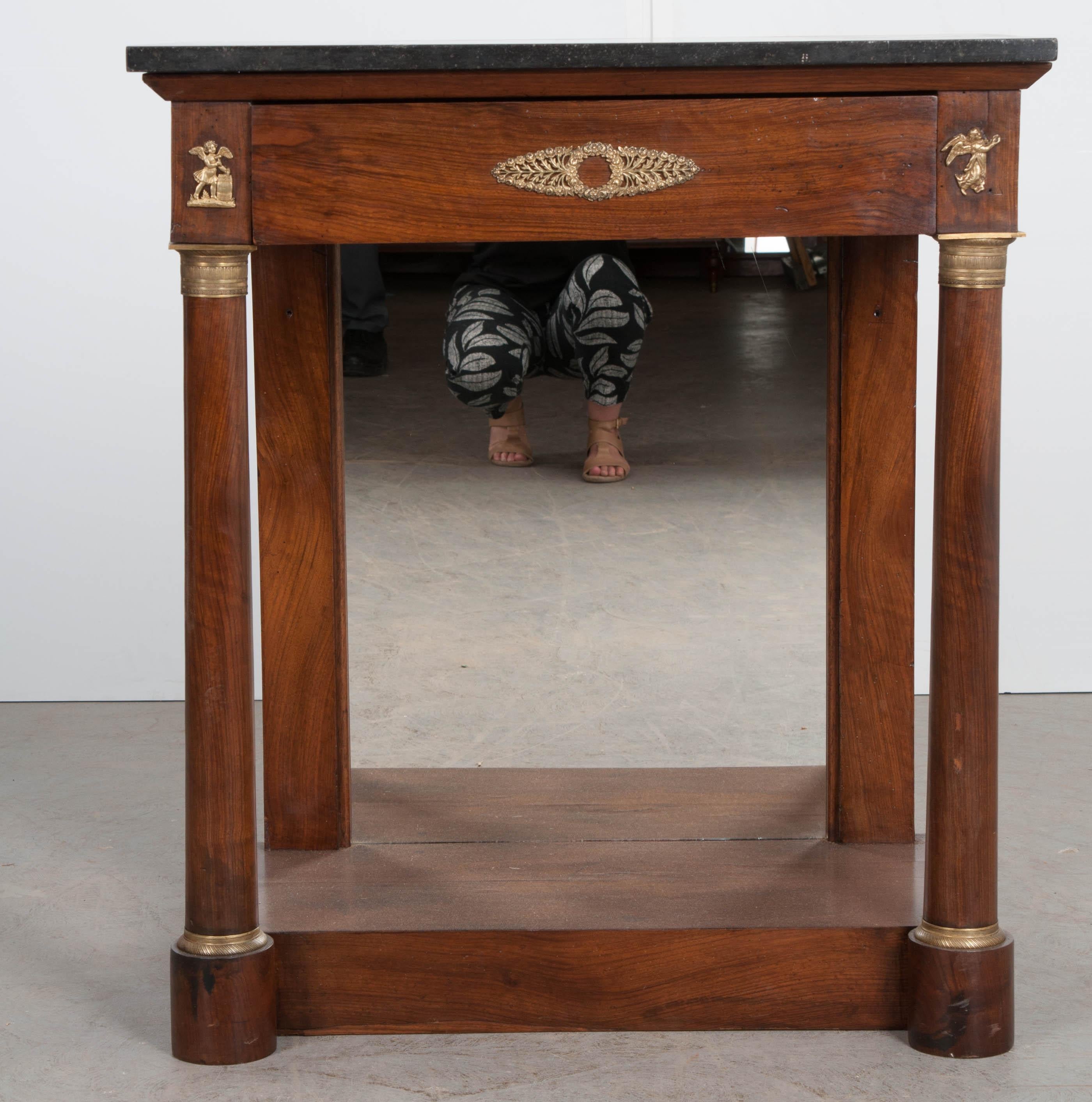 Topped in an exceptional piece of black antique marble, this 19th century empirically styled console was made in France, circa 1870. The conservatively styled console has clean lines and classic details. A drawer, with mahogany veneer and brass