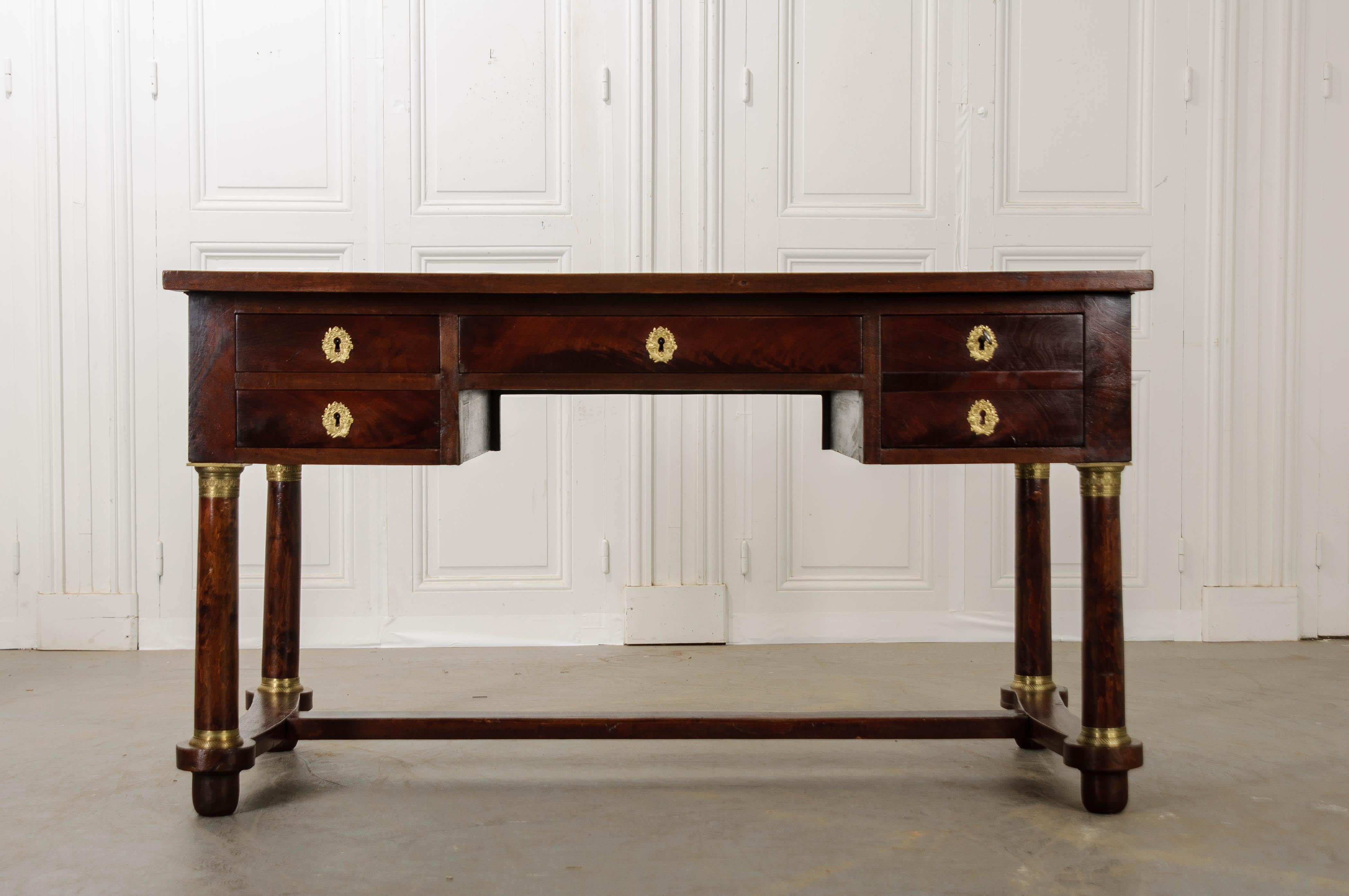 Emanate professionality from behind this stunning Empire-style mahogany desk, made in France circa 1890. The spacious desk is topped in beautifully tooled green leather. The desk’s work surface can be enlarged with a pull of either slide that is