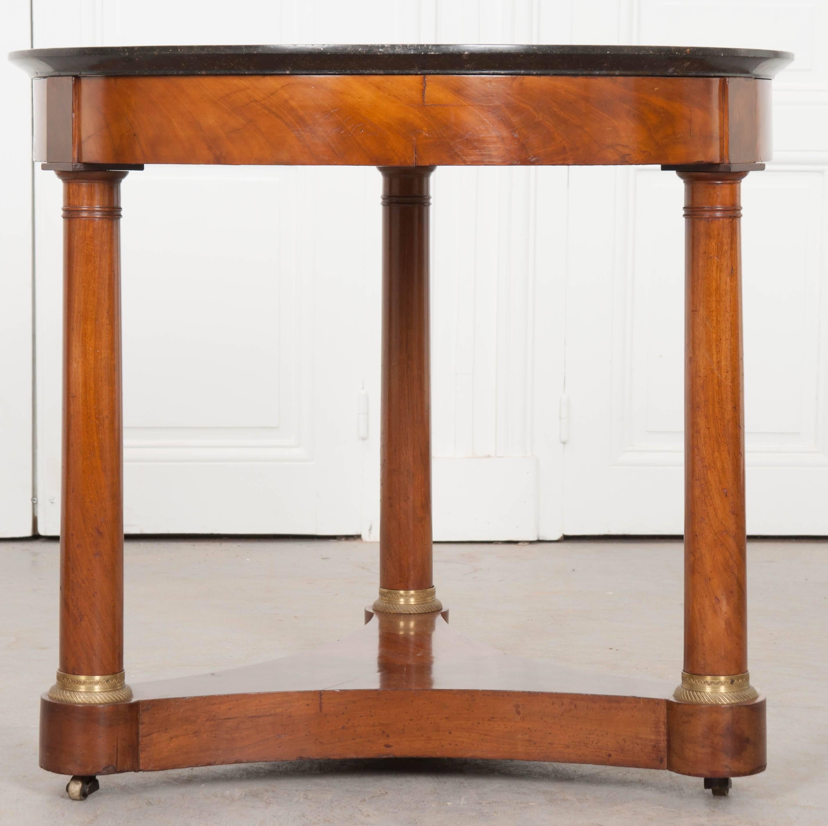 A rust-toned mahogany veneer has been artfully utilized in this stunning, 19th century French Gueridon. The table starts with an exceptional antique black fossil-marble top. A myriad of tiny creatures can be found in the stone, forever fossilized.