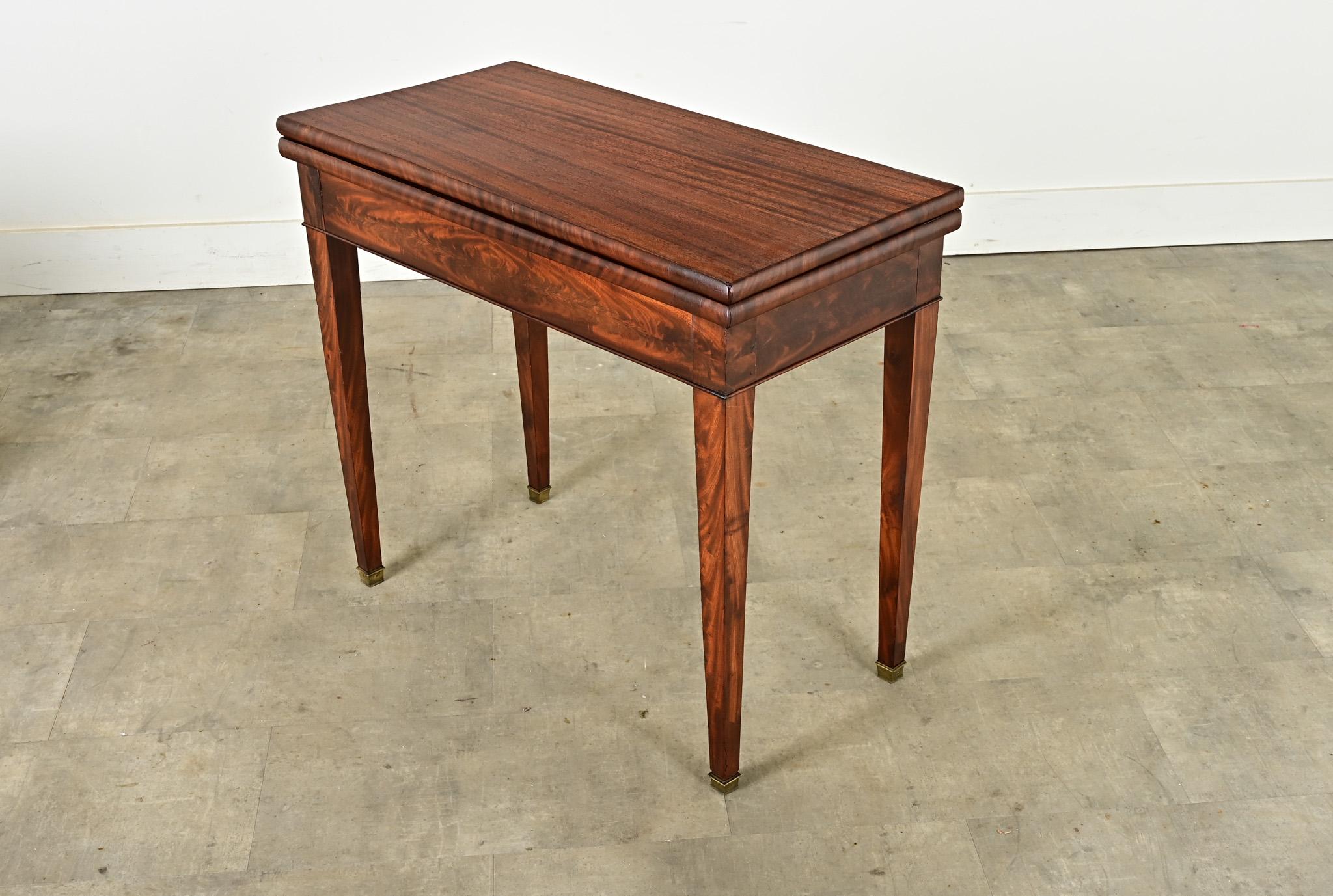 A versatile French mahogany console-game table from the late 1800’s. The rectangular tabletop flips open to become a square, revealing a green felt-lined interior surface that would be ideal for playing cards or rolling dice. Tucked away in the