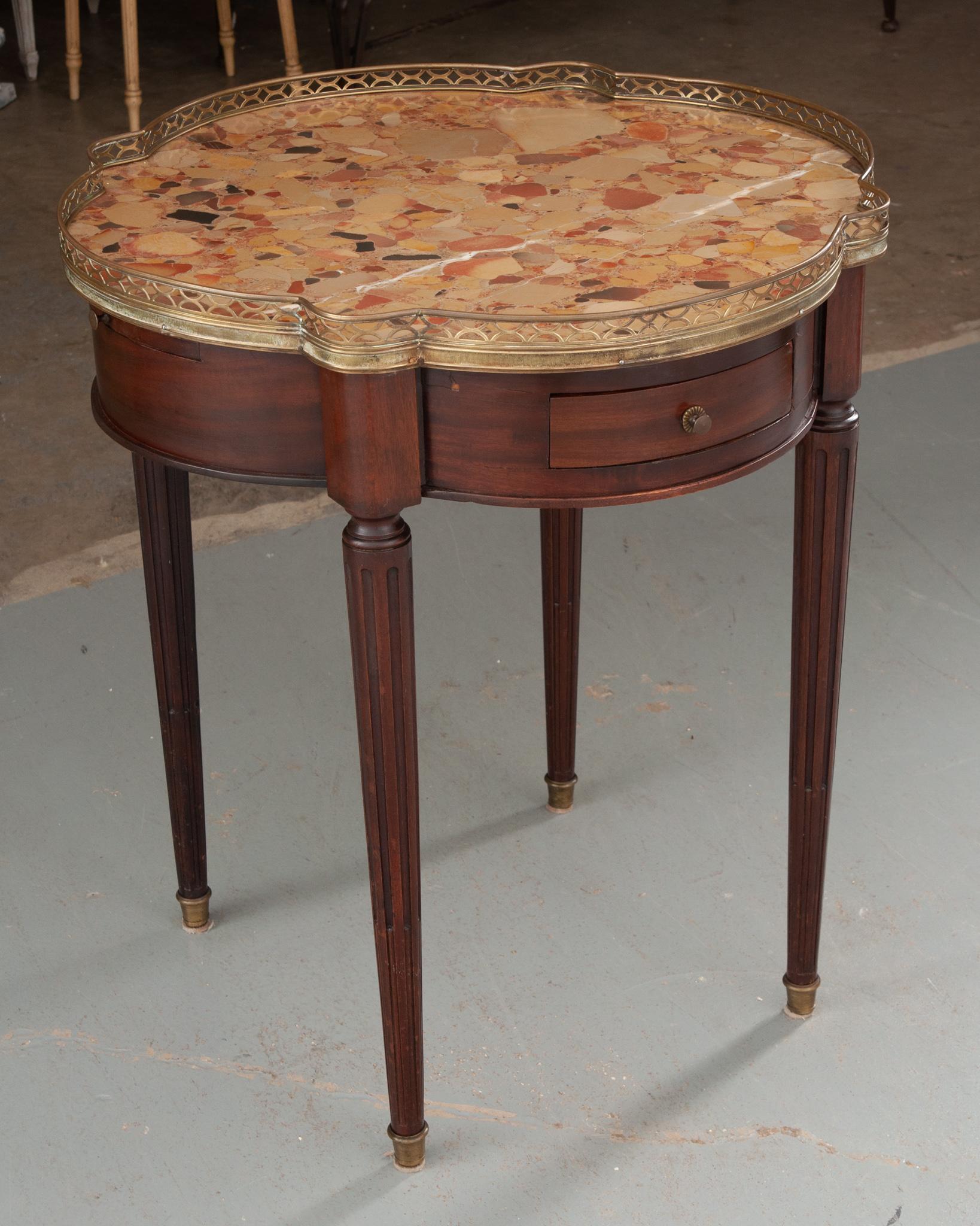 A wonderfully shaped gueridon from 19th century France. A delicate brass gallery encircles the quatrefoil shaped Breche d'Alep marble top. The turreted shaped apron, constructed with beautiful mahogany, houses two small drawers and two slides both