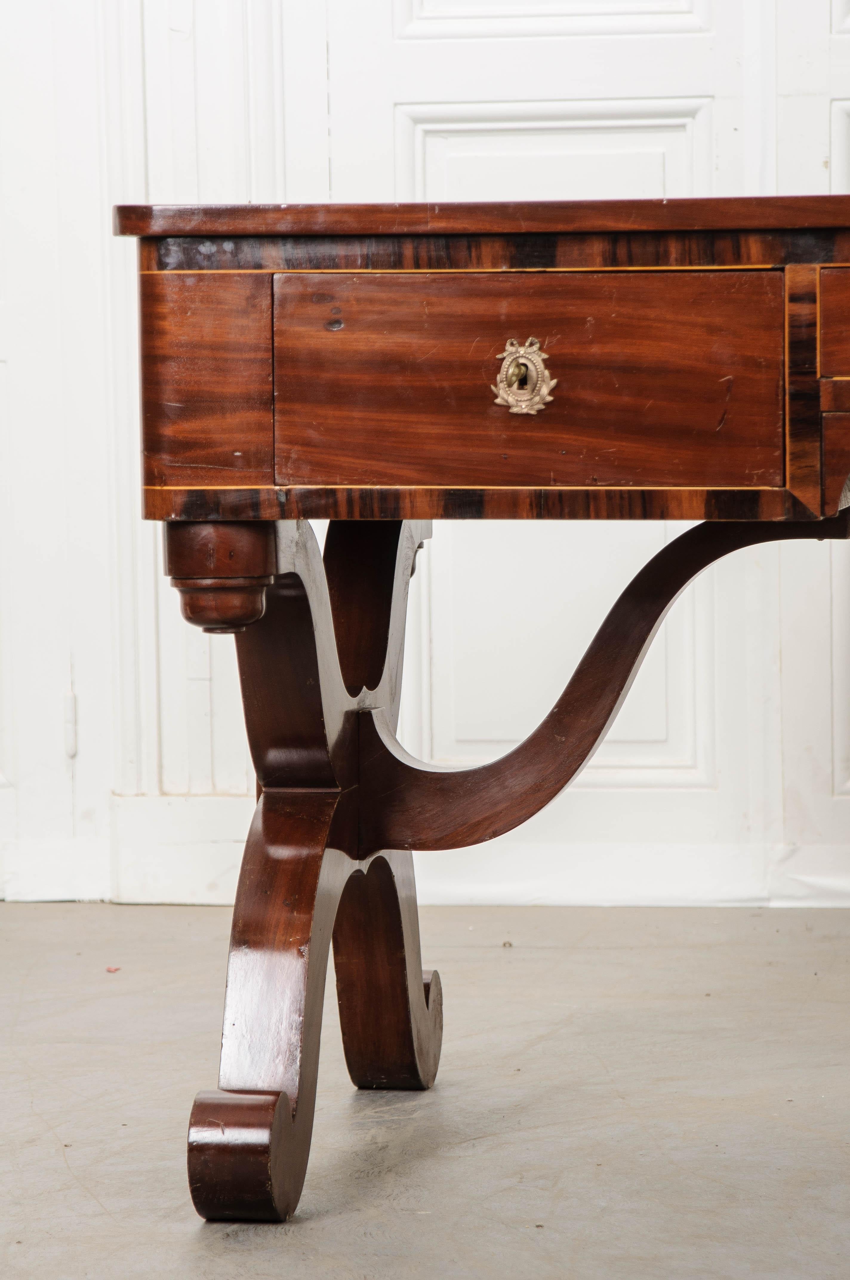 A large, leather-topped mahogany desk from 1870s, France. This exceptional antique incorporates elements of Empire, Restauration and Biedermier styles. The more darkly-toned mahogany is complemented by the desk’s camel-colored leather top, which has