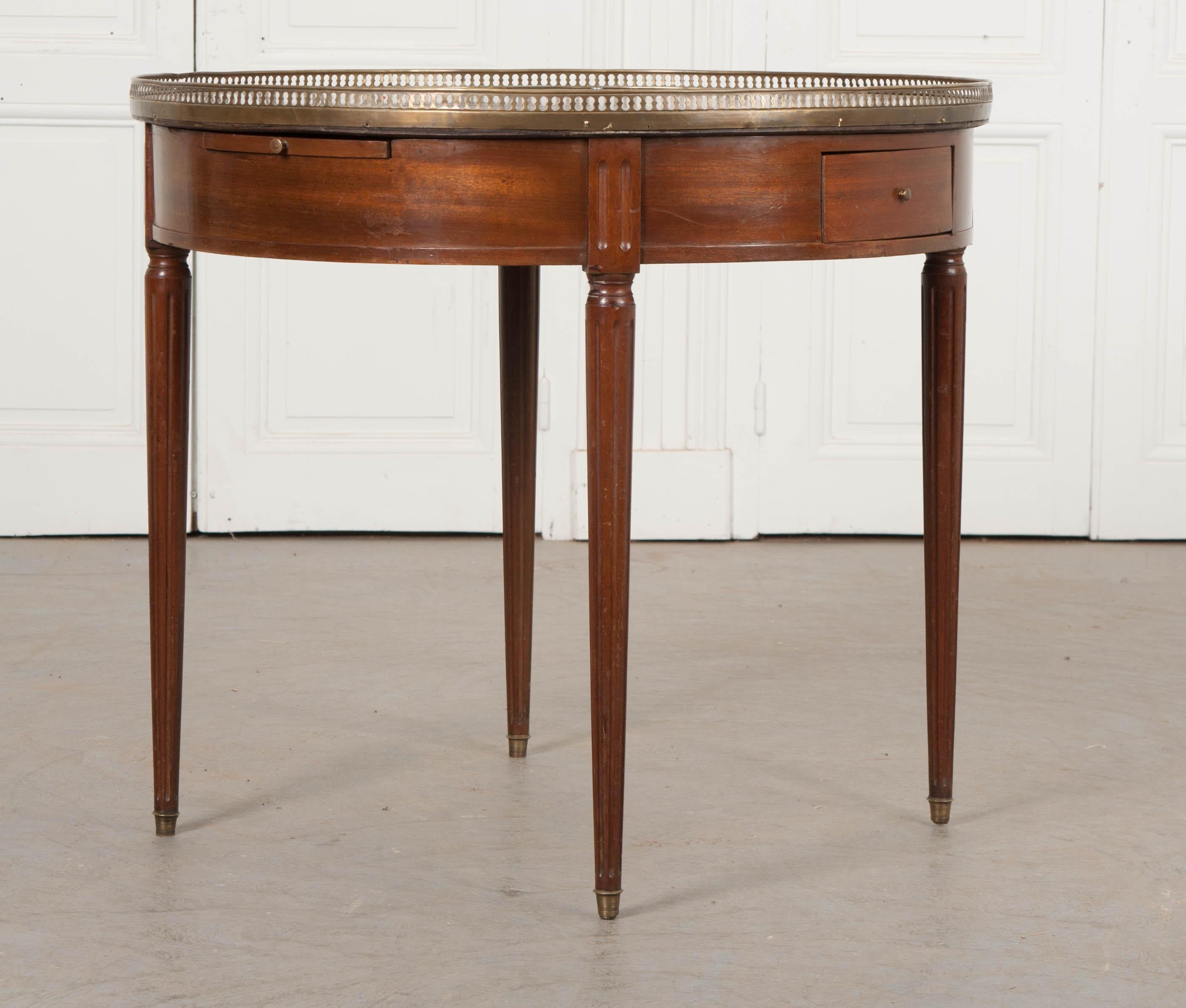 Gueridons that are this large are a rarity. This fine Louis XVI style circular mahogany gueridon table, circa 1880, is from France and features a gorgeous rouge marble top with grey and white veining, and reticulated brass gallery, above a pair of