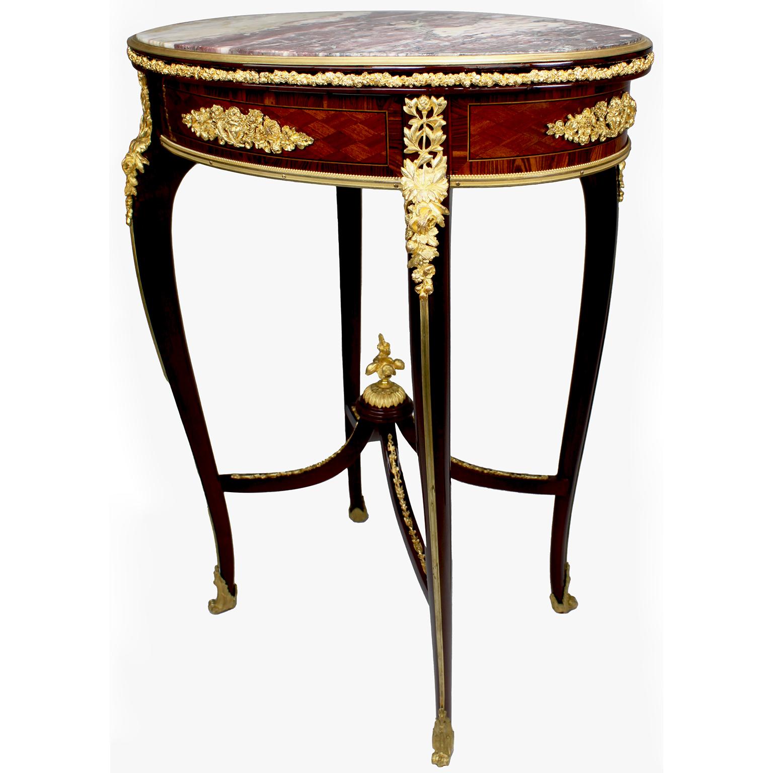Raffinato tavolino gueridon ovale in mogano, legno di tulipano, parquet e ormolu, in stile Luigi XV, con piano in marmo Brêche Violette, attribuito a François Linke (1855-1946). Il piano ovale in marmo Brêche Violette con contorno in bronzo dorato,