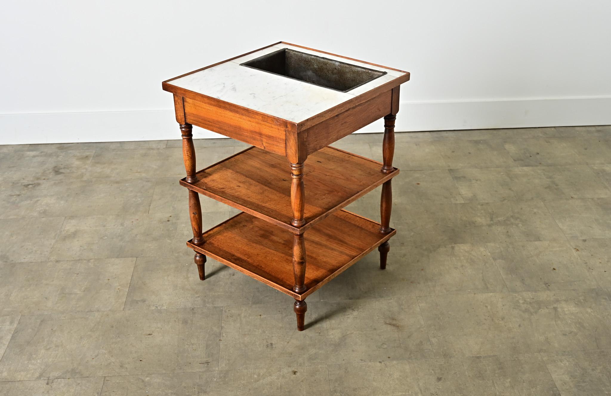 A French mahogany rafraîchissoir table from the late 19th century. Functioning like a dry bar, this occasional table is adapted to keeping beverages cold by placing them in a removable zinc trough set flush within the marble surface. Our example