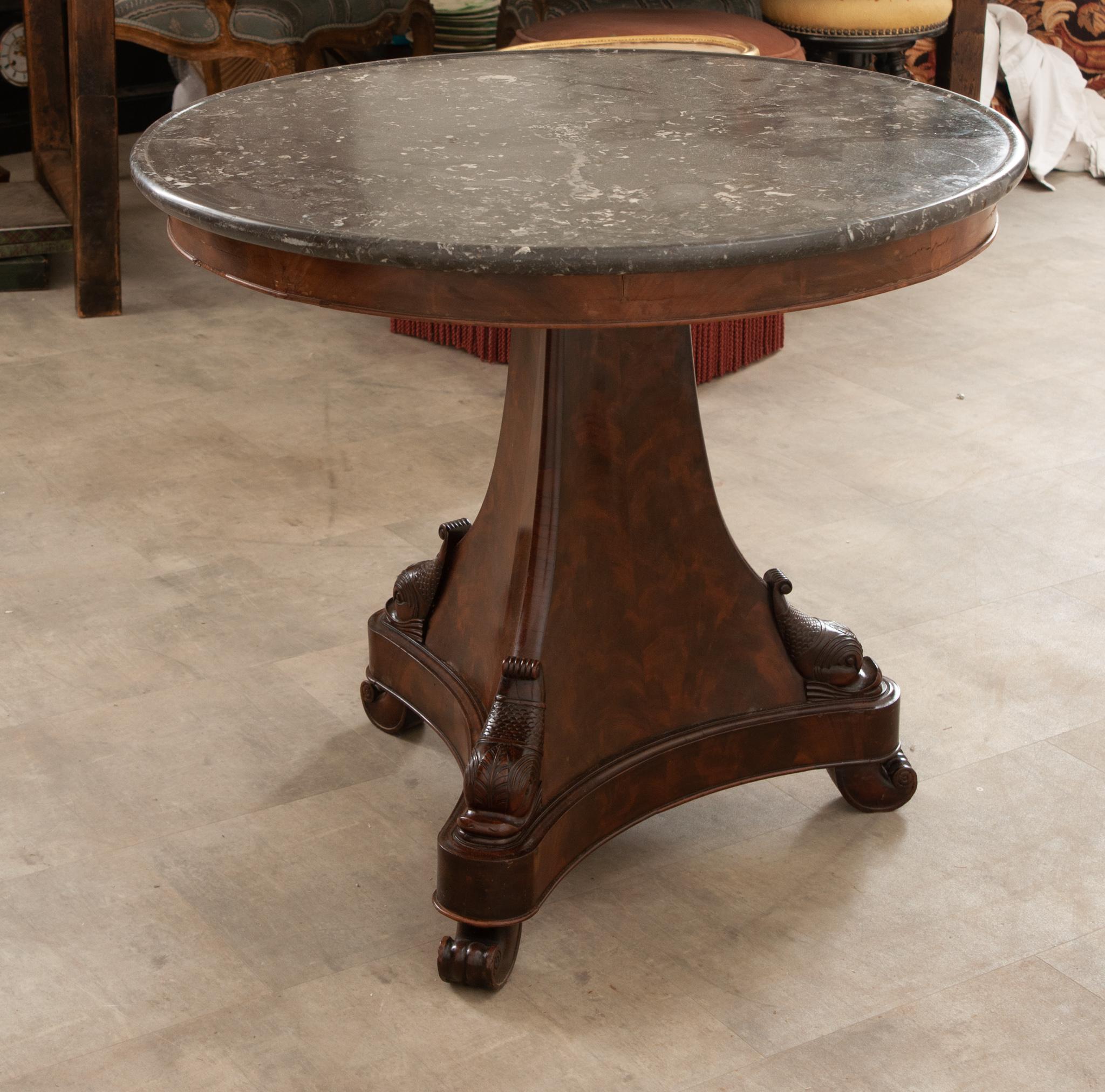 A quality French 19th Century Restauration style center table. Its sublime round marble top with gorgeous gray and white inclusions and veining throughout sits atop a marvelous hand-crafted mahogany trefoil stand that displays volute detailing with