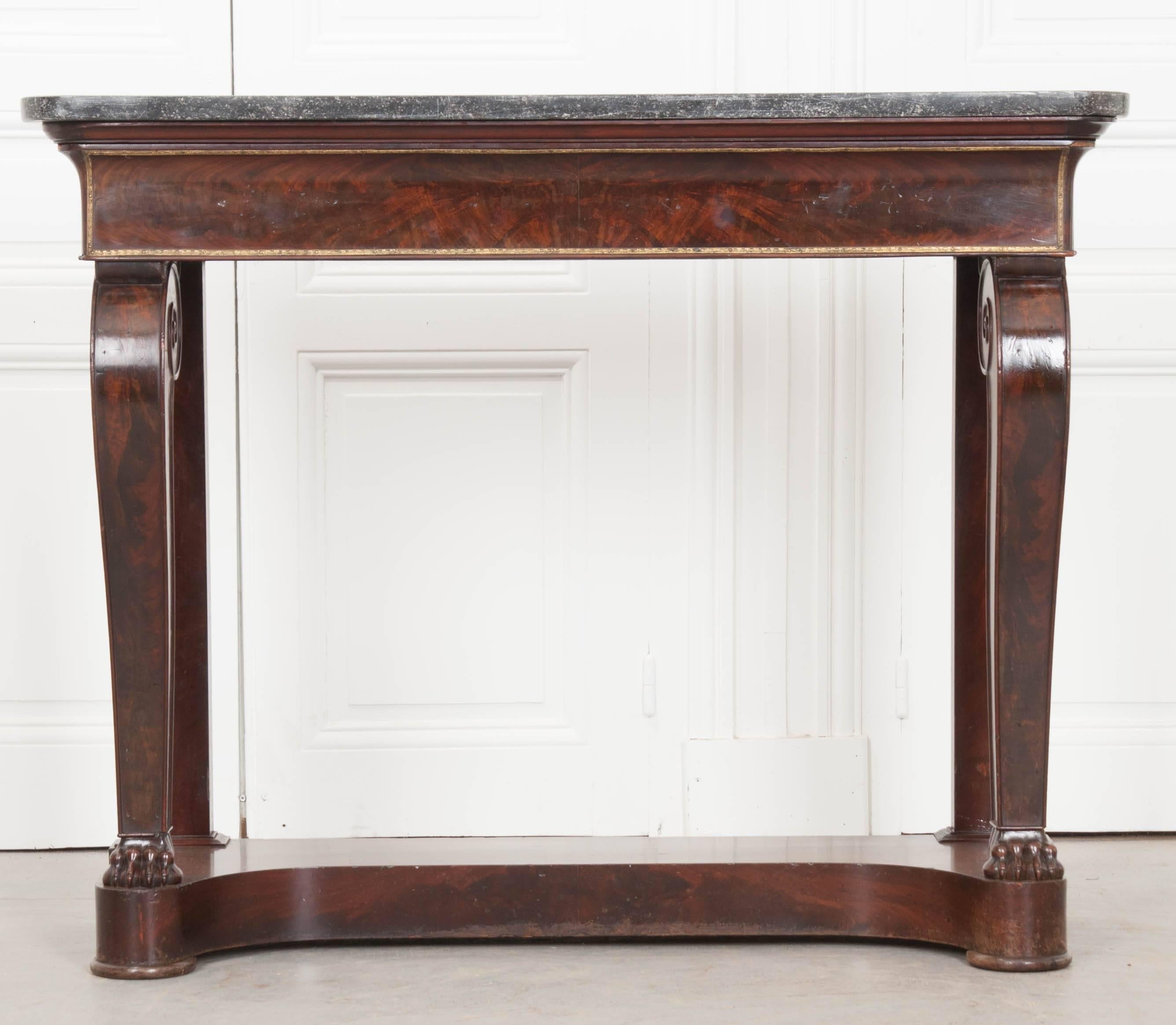 A handsome French console made in the Restauration style with a black fossil marble top. The marble top has rounded front corners, wonderful fossilized specimens, and rests atop a large hidden drawer that also functions as the table’s apron. This