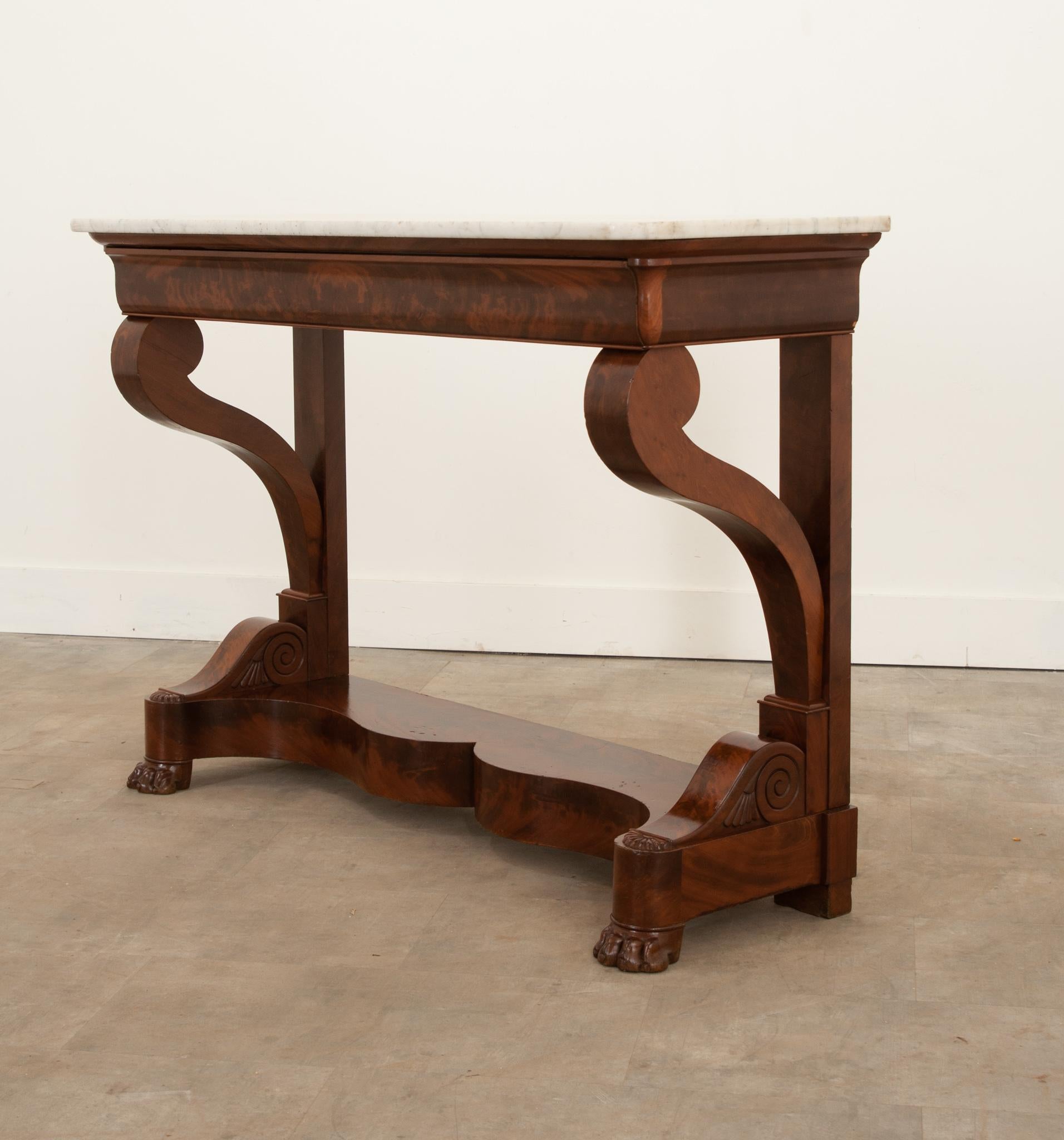 A great French mahogany console from the 1830s. The original white marble top elegantly cantilevers over its base and is Classic of the Restoration style. The entire design of this table has a hint of whimsy all the way down to the paw feet and
