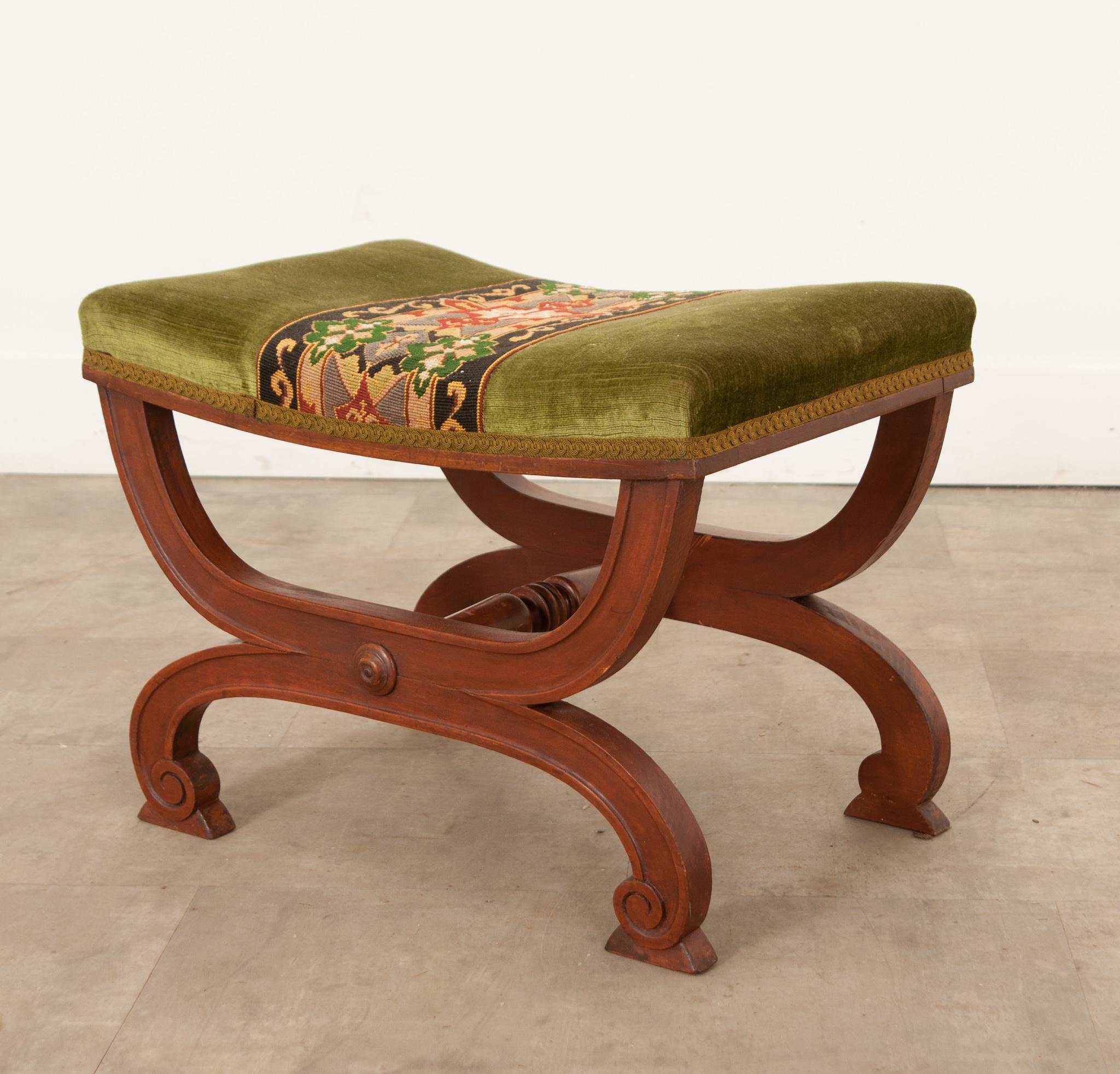 This fantastic petite stool is the perfect antique to dress up any space. Hand-crafted in France circa 1850, this stool is upholstered in green velvet with a beautiful needlepoint runner in the center and surrounded with ribbon trim covering the