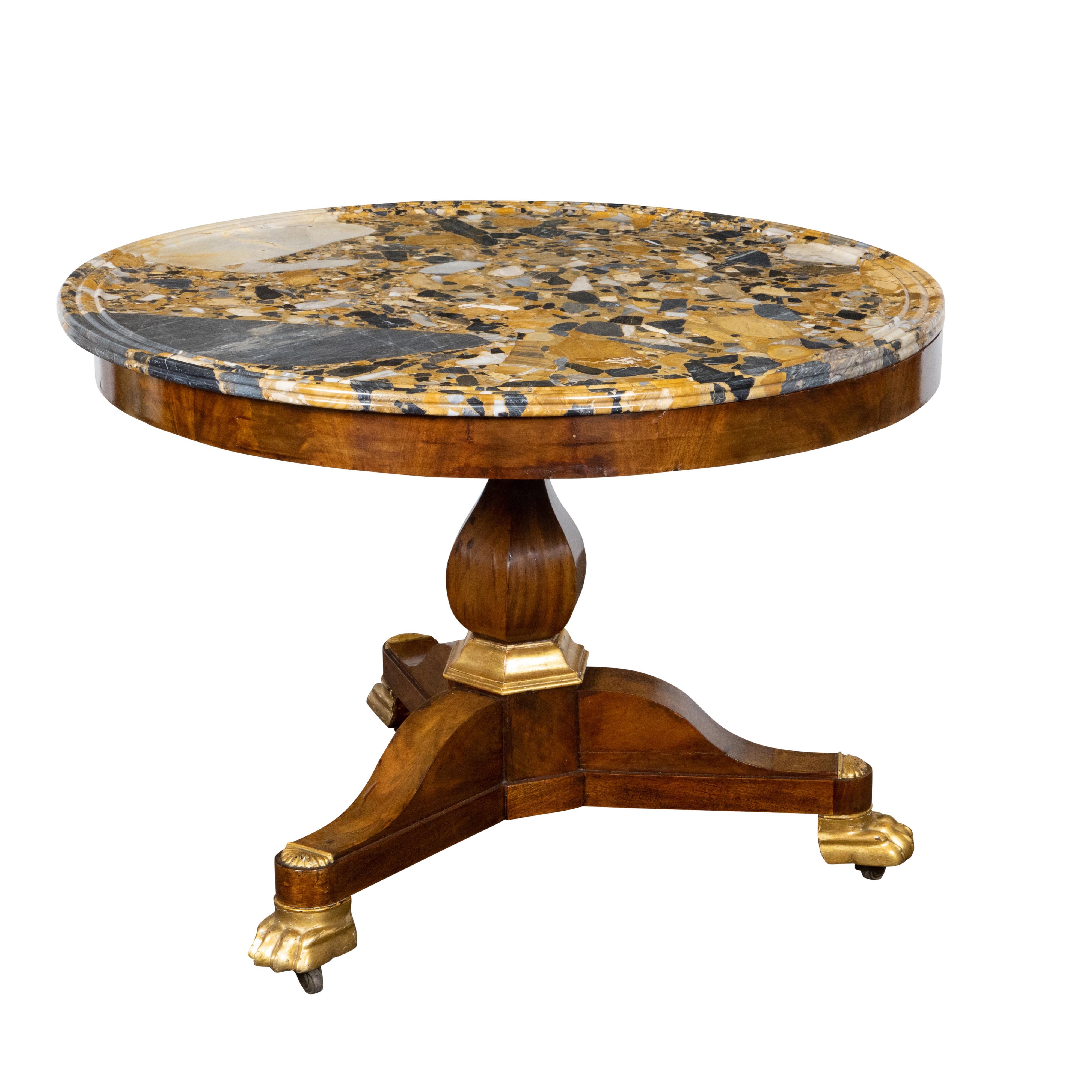A French Napoléon III period mahogany center table from the mid 19th century with colorful marble top, pedestal base and carved giltwood lion paw feet on casters. Created in France during the reign of France's last Emperor Napoléon III, this