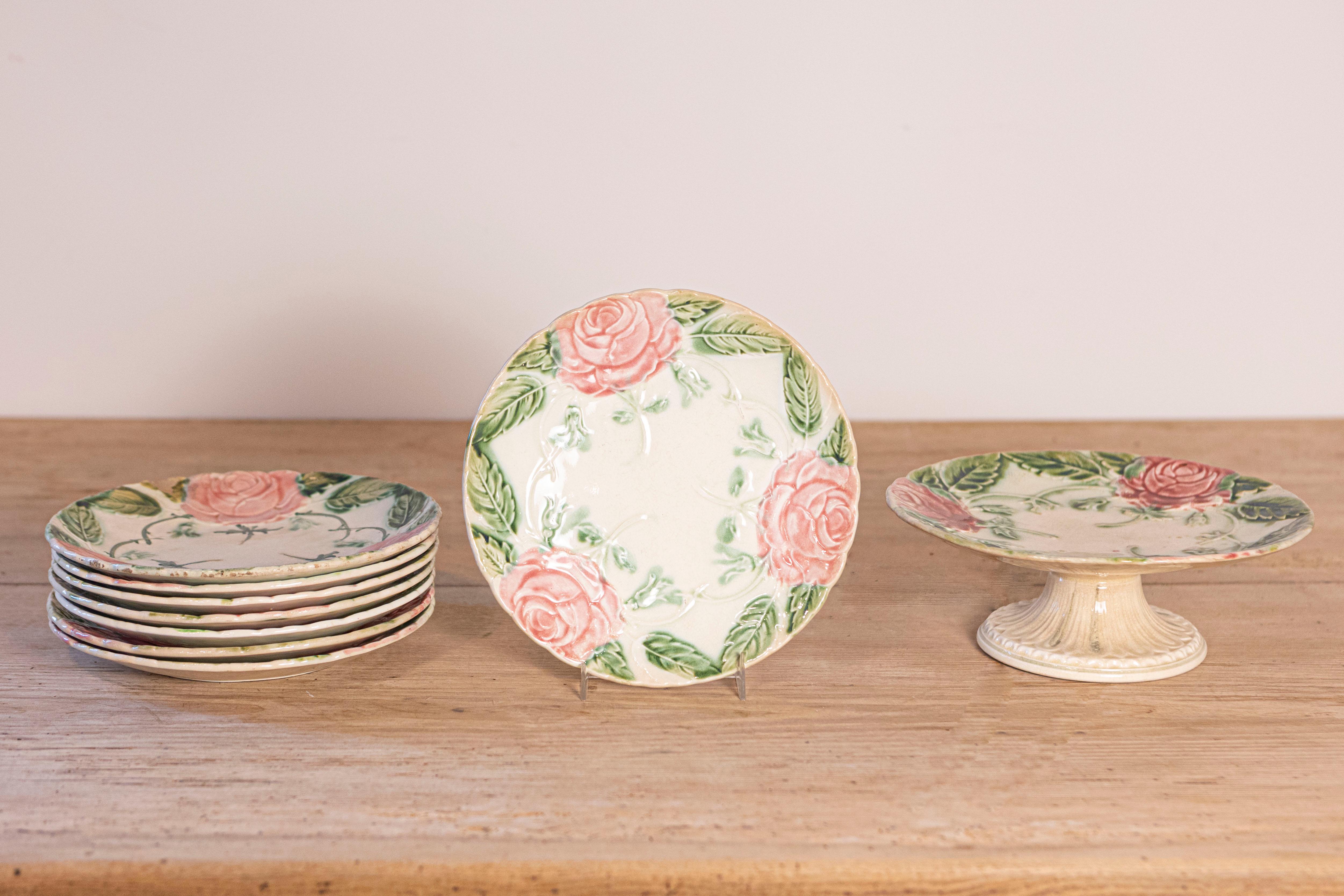 Une compote et sept assiettes en majolique française du 19e siècle, avec des roses et des feuillages, vendues individuellement. Nées en France au XIXe siècle, ces assiettes et compotiers en majolique charment notre regard par leurs tons rose et vert
