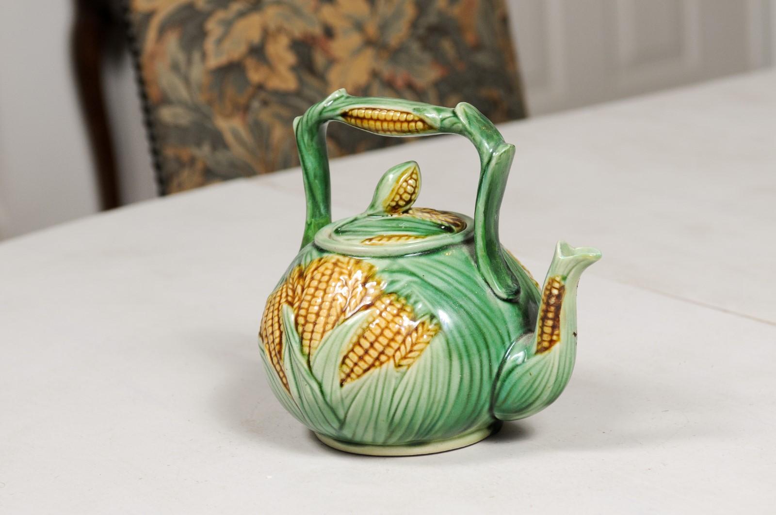 A French majolica lidded teapot from the 19th century, with green ground and corn motifs. Created in France during the 19th century, this majolica teapot features a circular body adorned with lucious green leaves from which corn stalks are emerging.