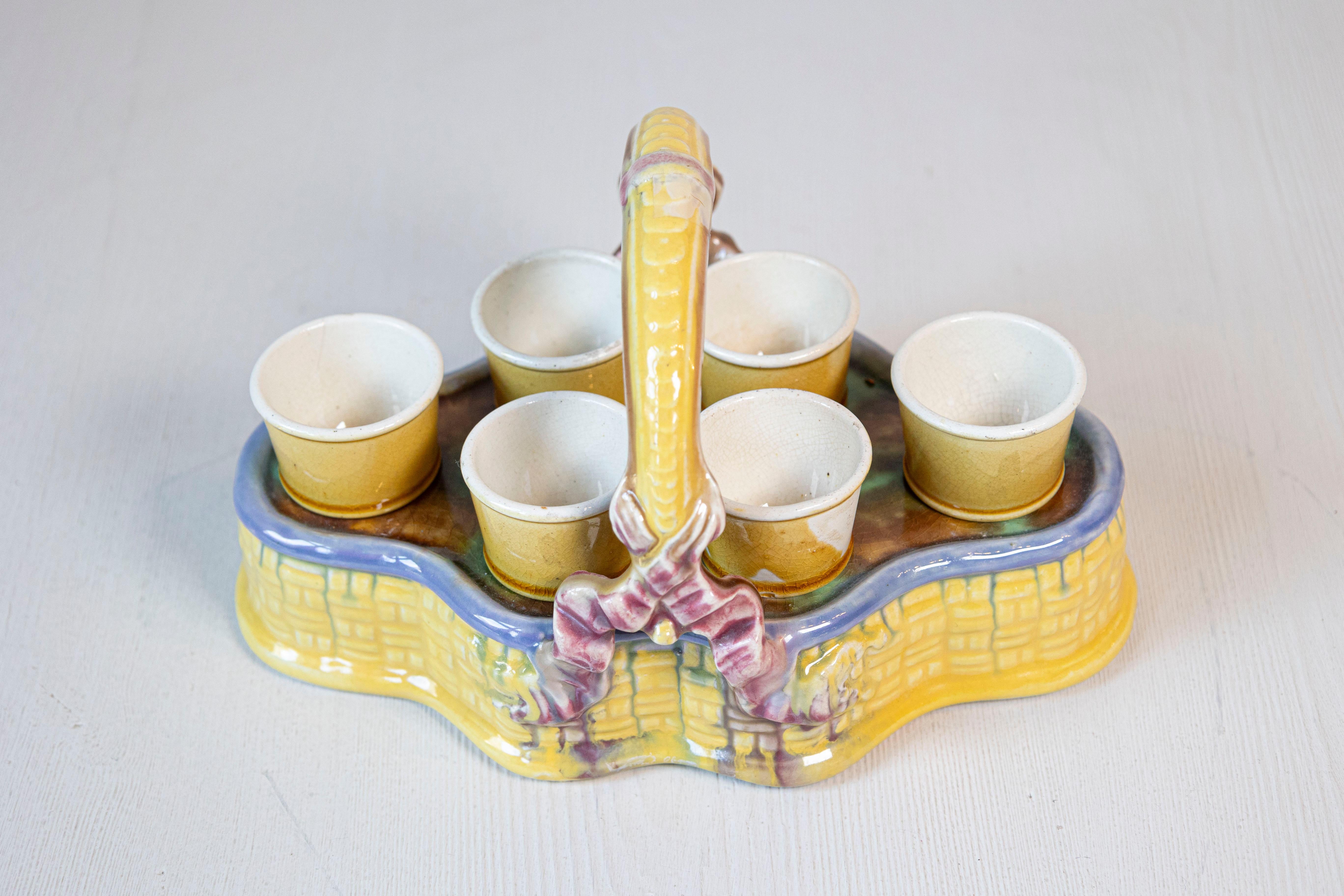 A French yellow glazed majolica porcelain basket from the 19th century, with a set of six egg cups and pink ribbons. Created in France during the 19th century, this majolica porcelain basket draws our attention with its lovely yellow glaze perfectly