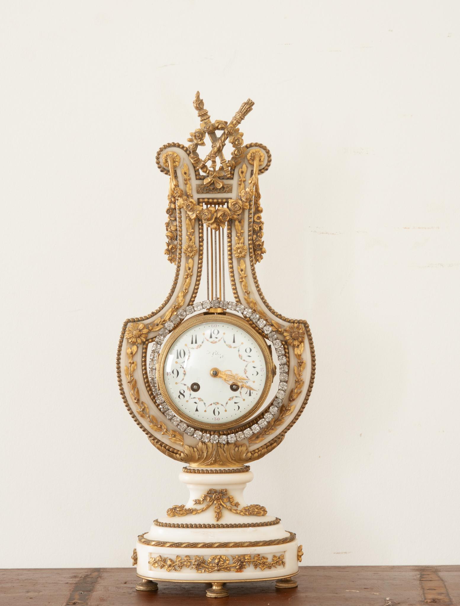 This fabulous mantle clock is the perfect way to add a touch of sparkle to any space. Crafted from wonderfully shaped white marble that’s been adorned with gorgeous ormolu. Atop the whole is a floral wreath that’s crossed with a pair of torches