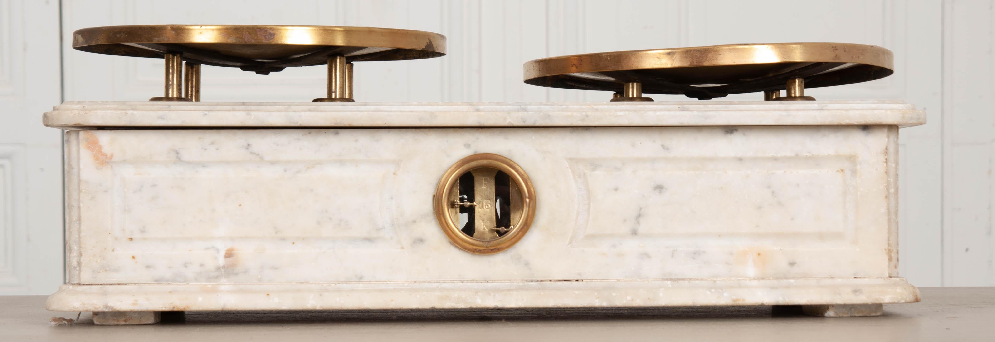 An amazing 19th century French culinary scale, made of marble, with original brass plateaux. The plateaux are handsomely patinated and bear numerous stamps, left by officials at previous occasions when the machine was calibrated. The scale is made