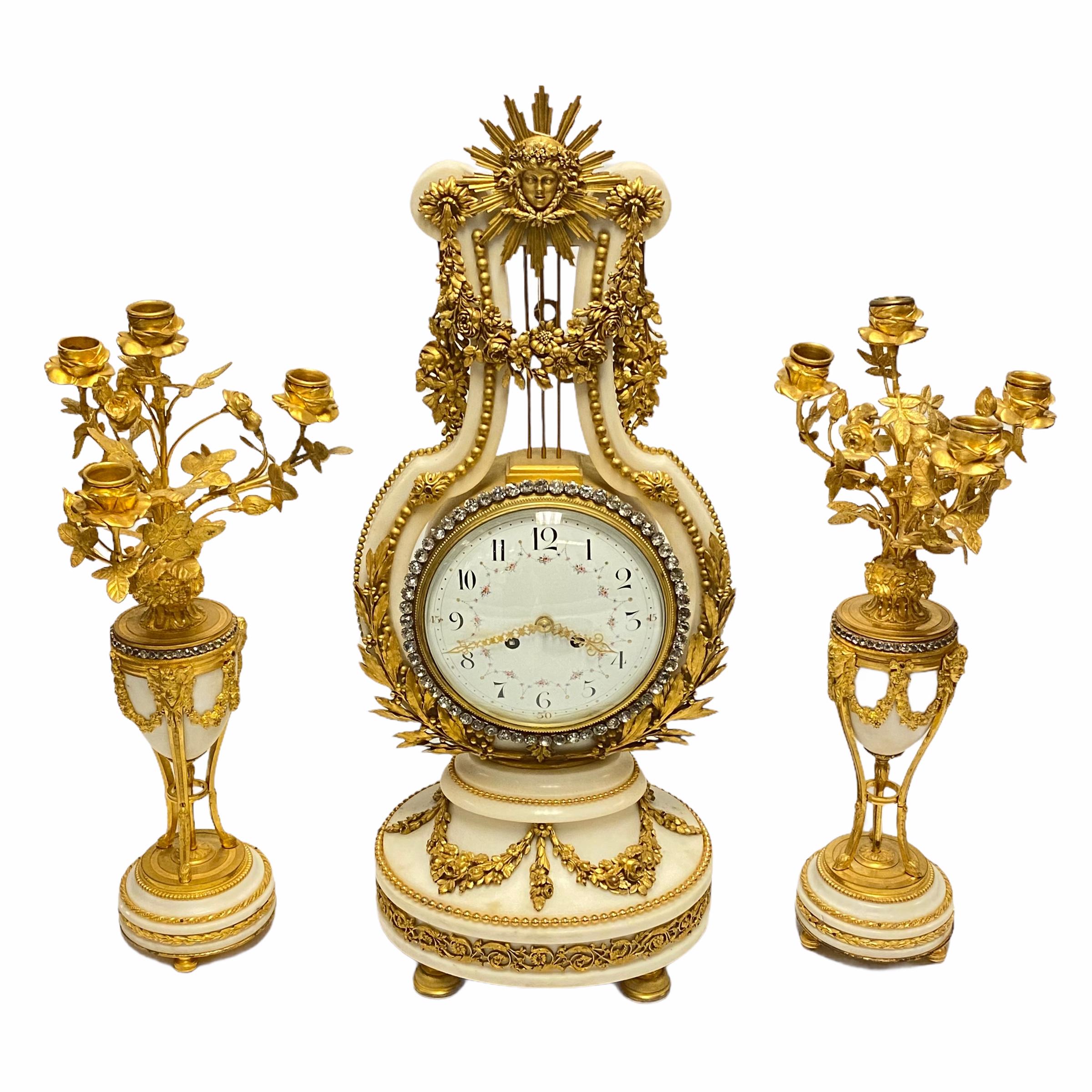 A very fine quality French 19th century clock and garniture suite. Comprising an ormolu-mounted white marble mantel clock and a pair of gilt bronze and white marble candelabras. Clock is decorated with simulated glass diamonds, movement is stamped