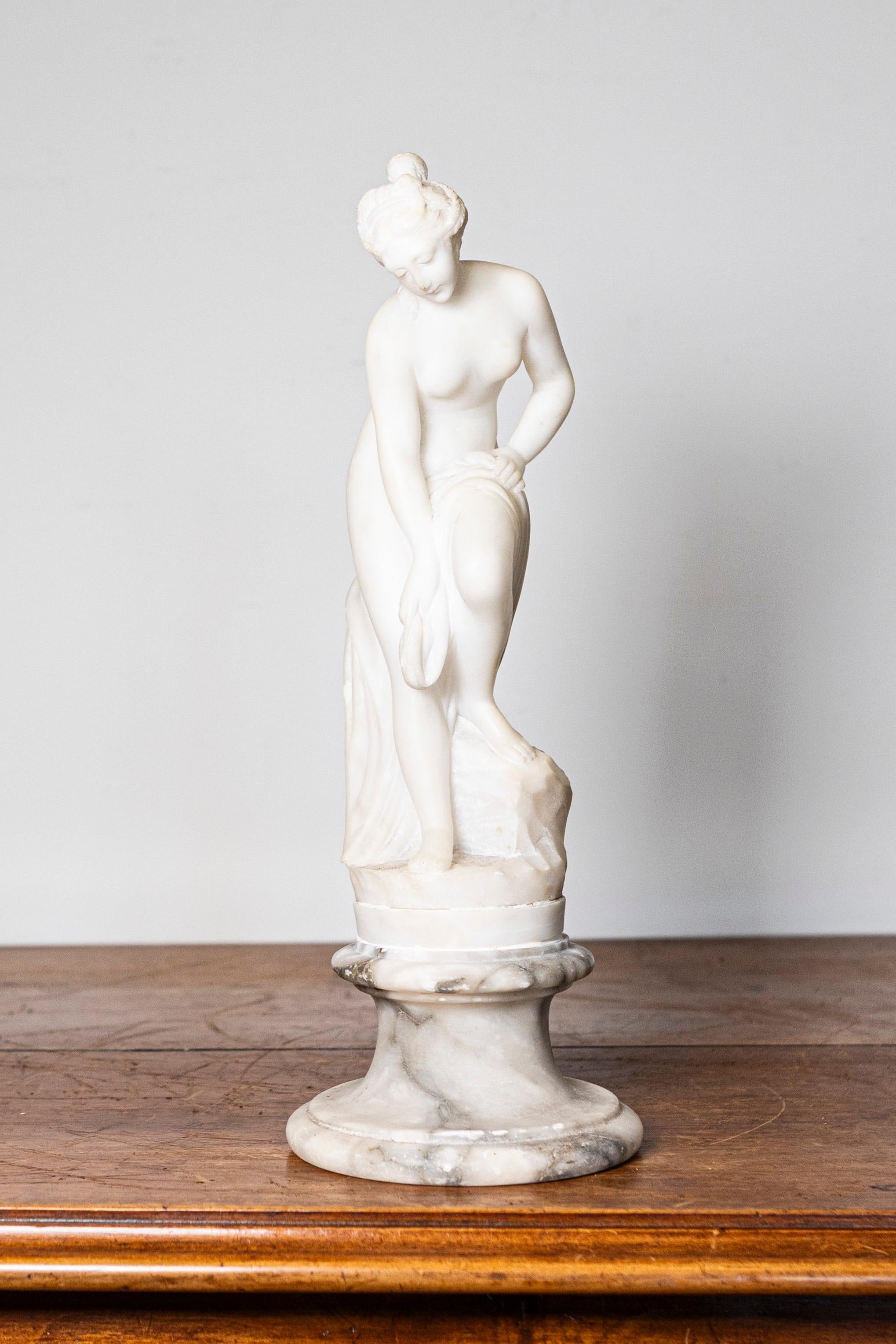 Scultura in marmo in stile neoclassico francese del XIX secolo che raffigura una ninfa dopo il bagno su una base di marmo grigio e bianco. Questa squisita scultura in marmo in stile neoclassico francese del XIX secolo cattura l'eleganza e la grazia