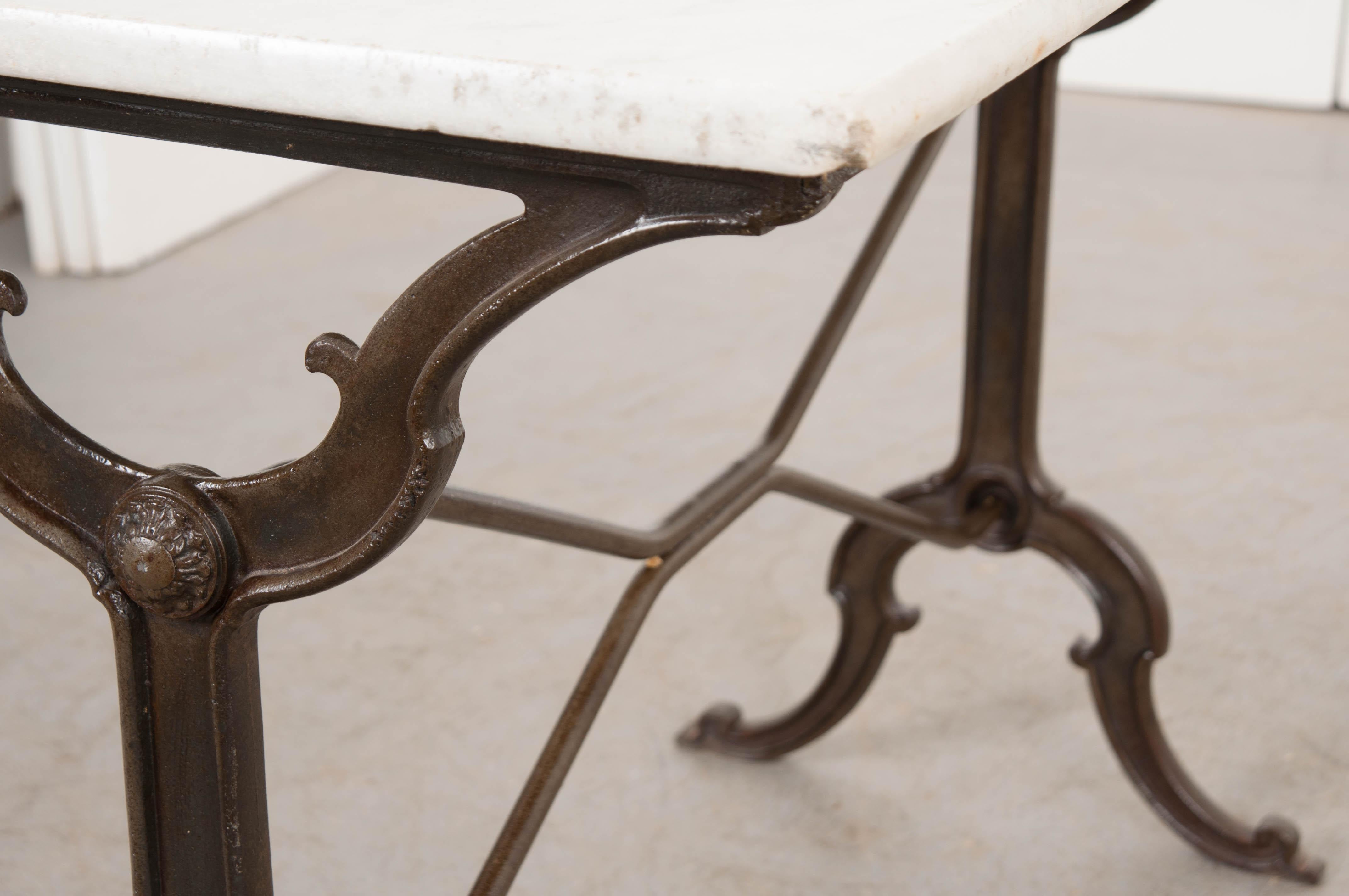 A charming French marble-top garden table, circa 1890s, with a classically styled iron base. The white marble top has beautiful inclusions throughout and the base has X-form supports and the scroll-form feet. This wonderful table is not confined to