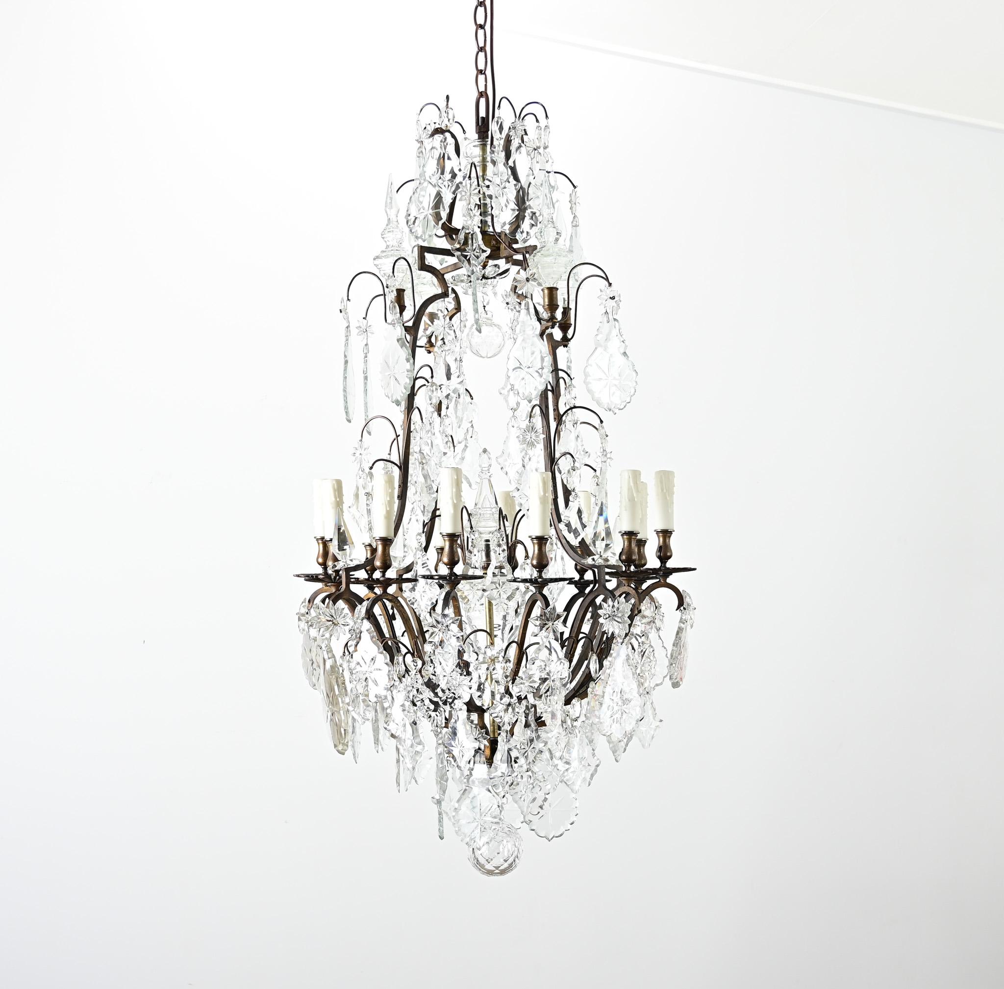 A fabulous and large 19th century French twelve light bronze and crystal chandelier to illuminate your dining room, foyer, or other glamorous setting. This statement chandelier has a multi-tiered dark bronze frame that is dense with cut crystal