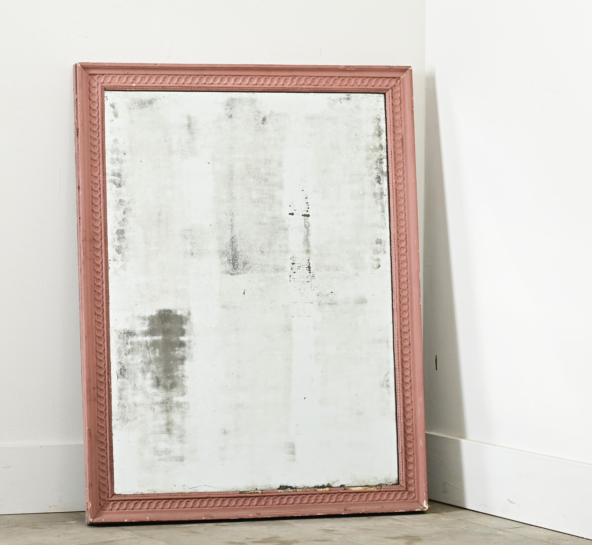 Ce miroir français classique du XIXe siècle (qui est symétrique pour être monté dans n'importe quelle orientation) a été récemment mis à jour avec une peinture rose mauve pour lui donner une nouvelle esthétique plus décontractée. La texture usée par