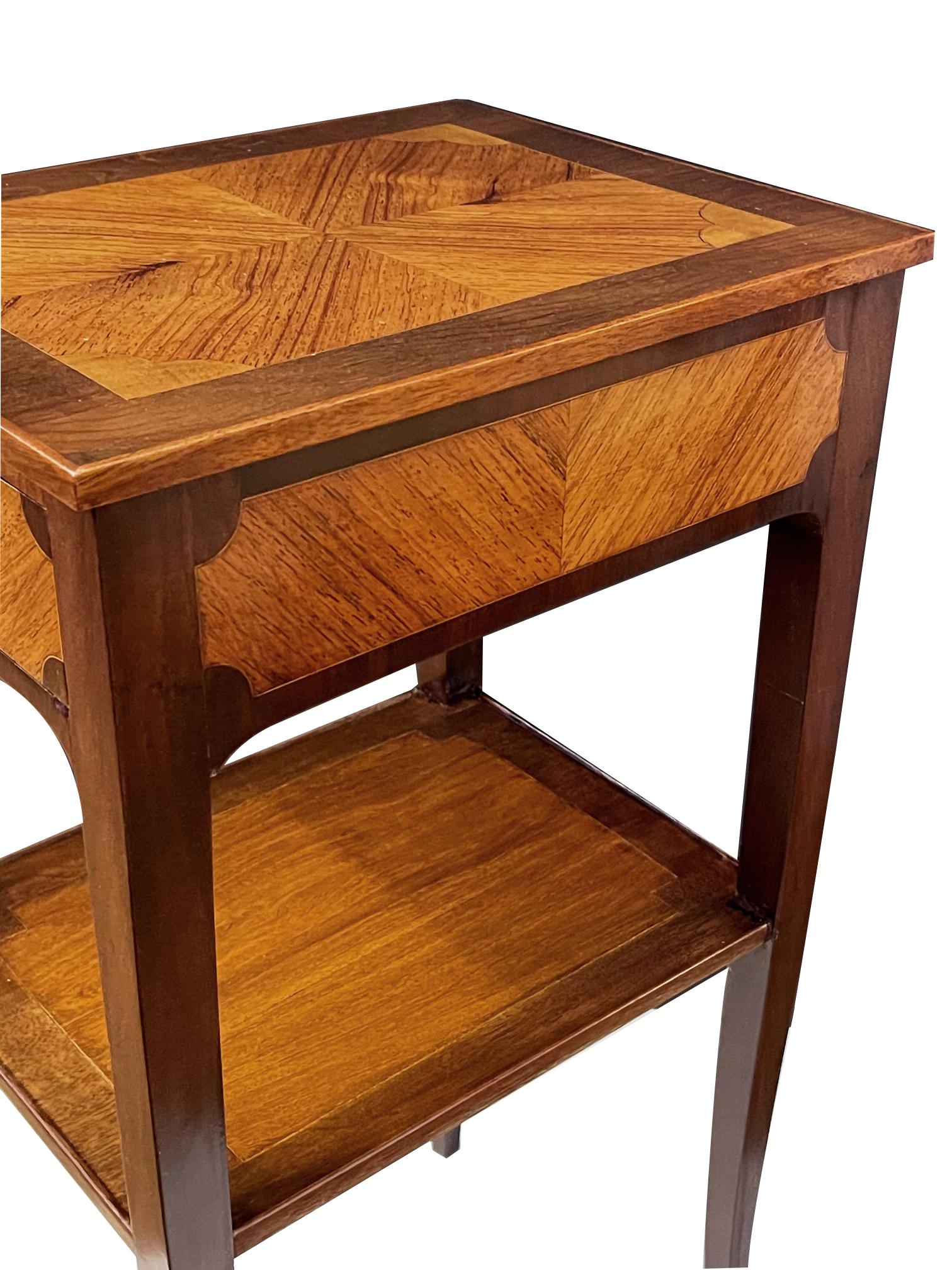 The rectangular top centering bookmatched Kingwood veneer within a walnut border; over a conforming apron fitted with a single drawer with similar veneer all raised on graceful splayed legs joined by a lower shelf.