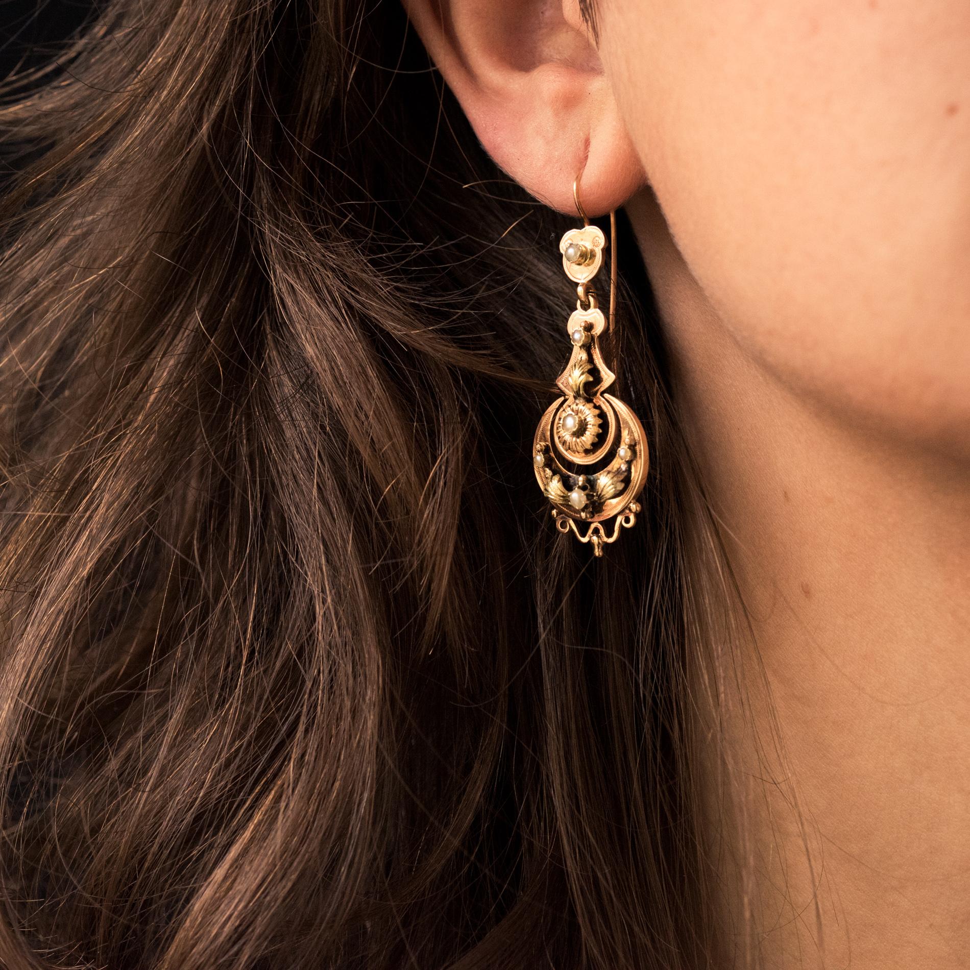For pierced ears.
Pair of earrings in 18 karat rose and yellow gold, eagle's head hallmark.
Each pendant has a floral and plant motif enhanced with natural pearls, with a moving part in the center, all retained by a small shield set with a natural