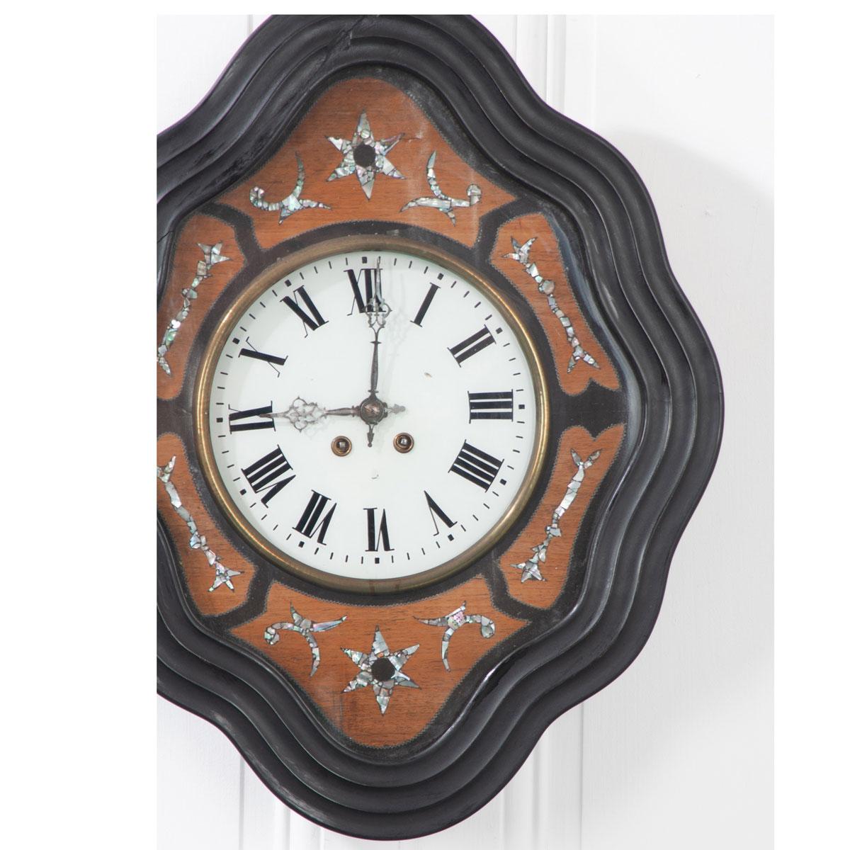 Superbe horloge murale du XIXe siècle, en forme de diamant, avec un cadre d'horloge ondulé en bois peint en ébène. Des motifs astraux et filigranes en nacre sont incrustés dans de l'acajou teinté différemment et de la nacre brillante, entourant le