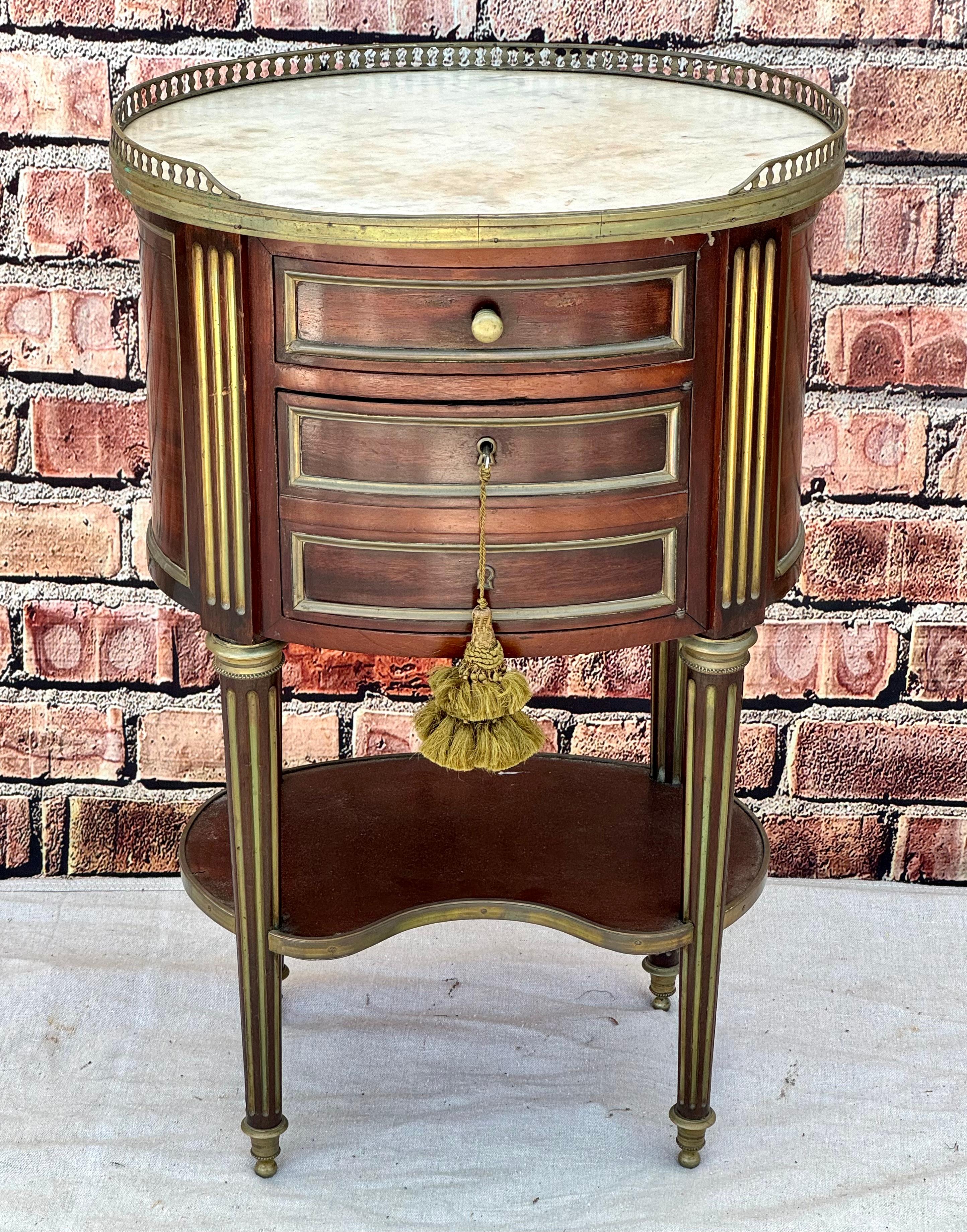 French 19th Century Napoleon III Oval Marble Top Side Table. Table has an oval form with a three quarter brass gallery surround over a white marble top, over a short drawer and a faux drawer facade' door. All sits on corseted and fluted legs joined