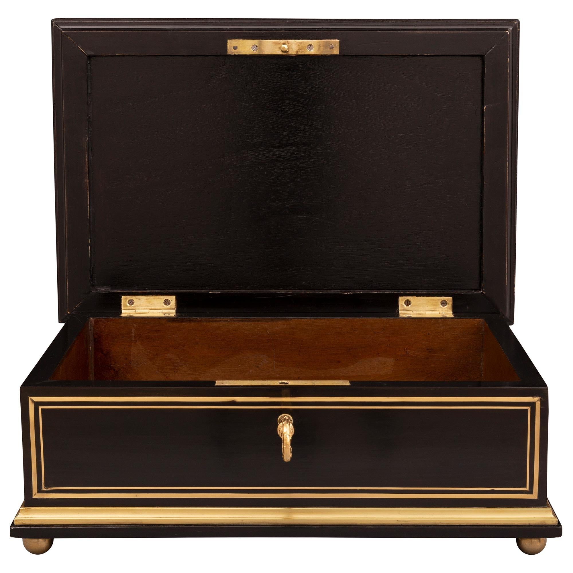 Un elegantissimo cofanetto francese del XIX secolo del periodo di Napoleone III in ebano, ormolu e ottone. La scatola è sollevata da raffinati piedini a sfera in ormolu sotto una bella fascia screziata avvolgente. Ogni lato in ebano è incorniciato
